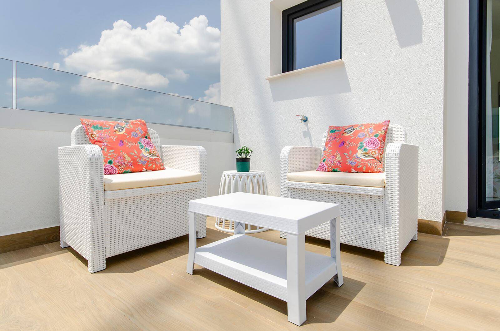 Heller Balkon mit bequemen Korbsesseln und Blick auf die Umgebung.