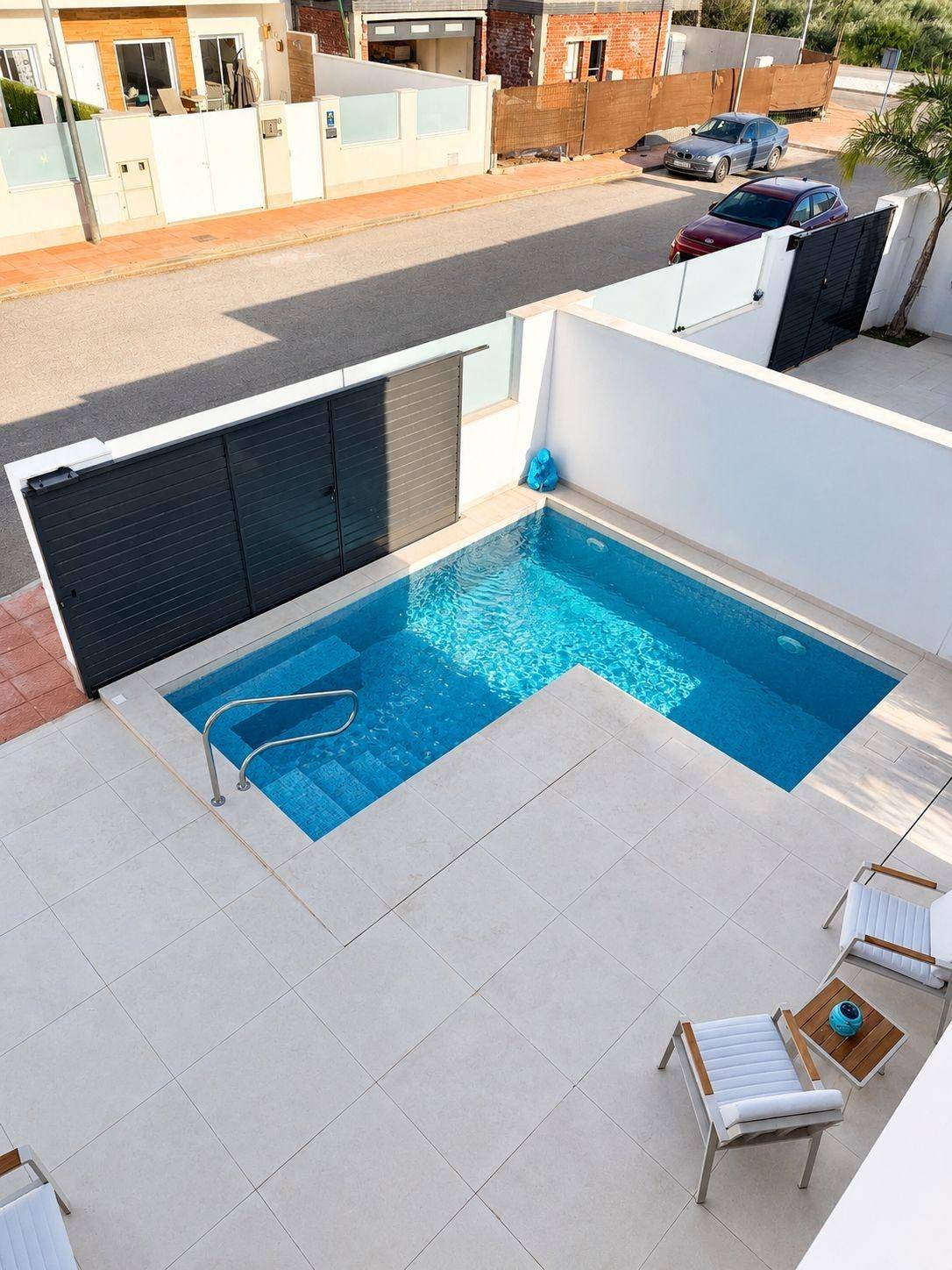 Vogelperspektive auf den privaten Poolbereich mit Terrasse und angrenzender Straße.