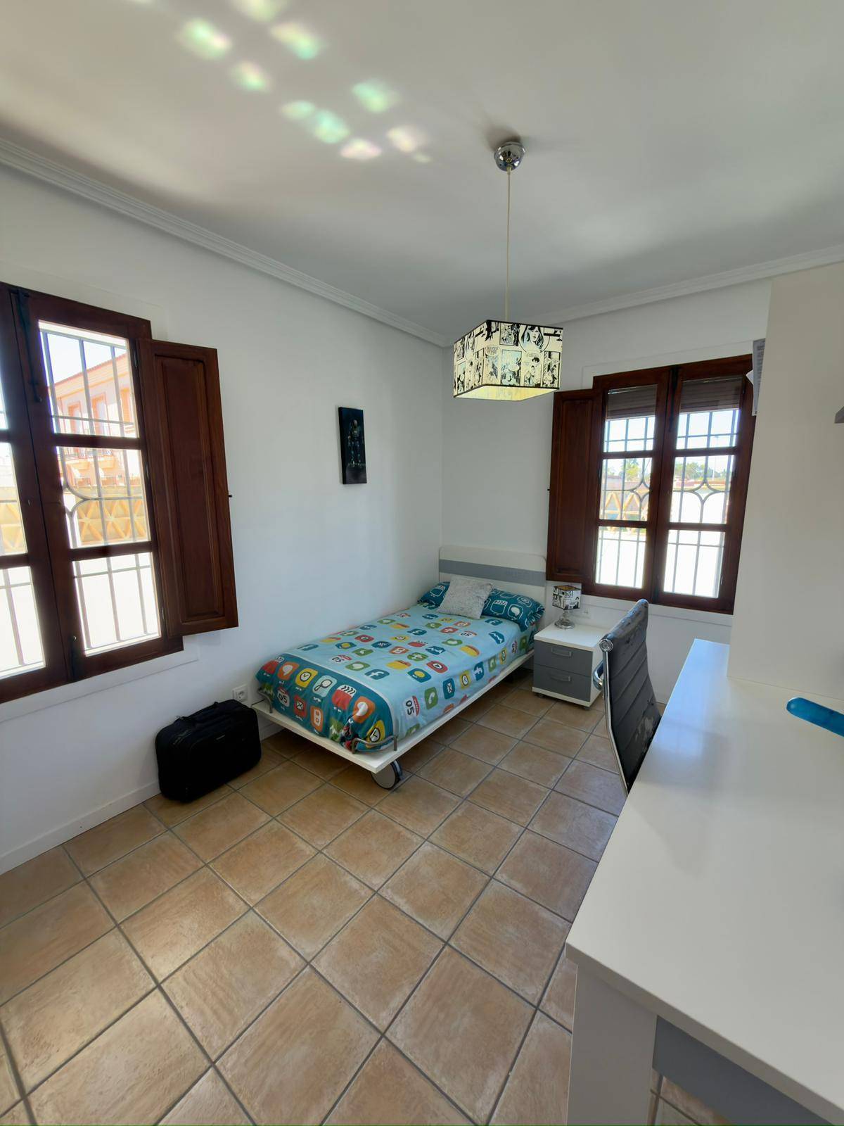 Schlafzimmer mit Einzelbett, Schreibtisch und zwei Fenstern für viel Tageslicht.