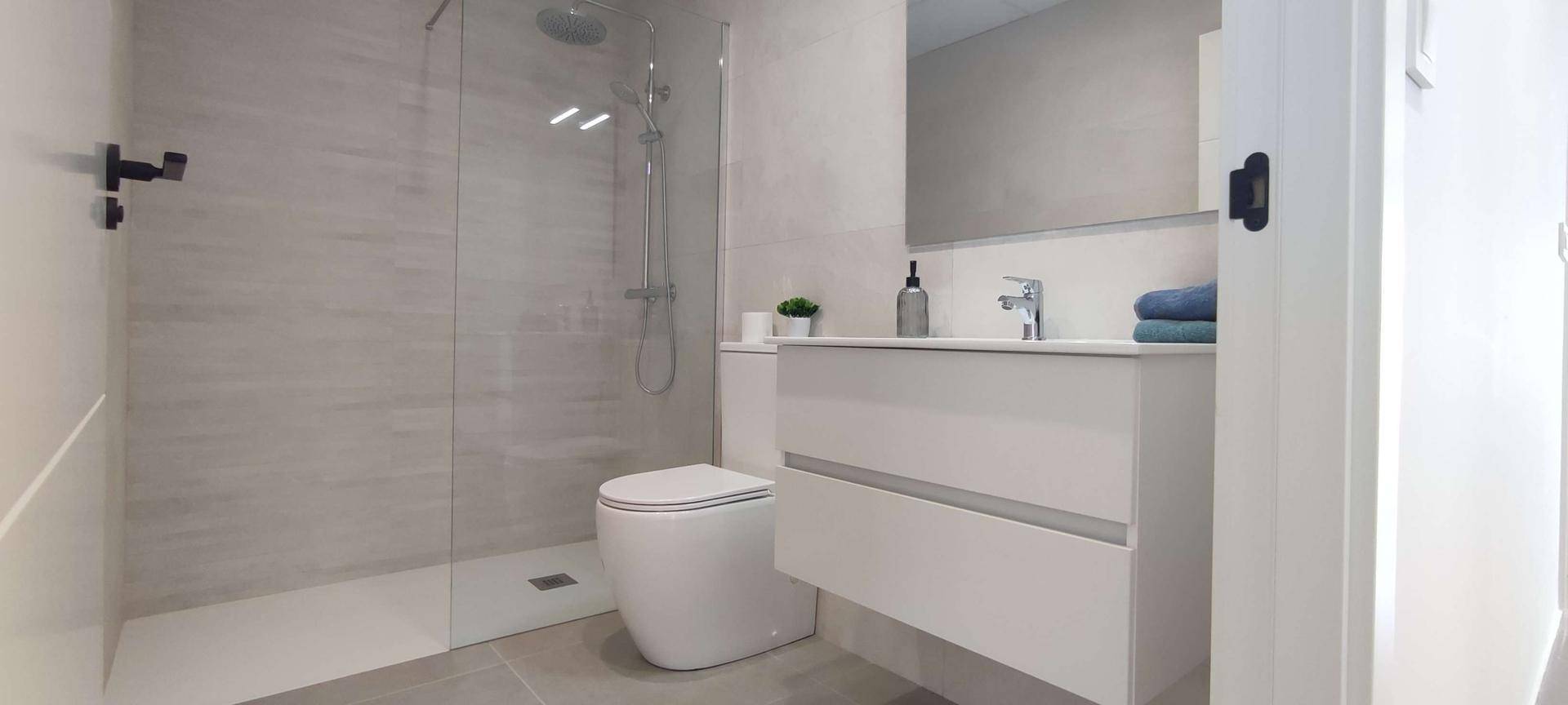 Modernes Badezimmer mit ebenerdiger Dusche, wandhängendem WC und stilvollem Waschtisch.