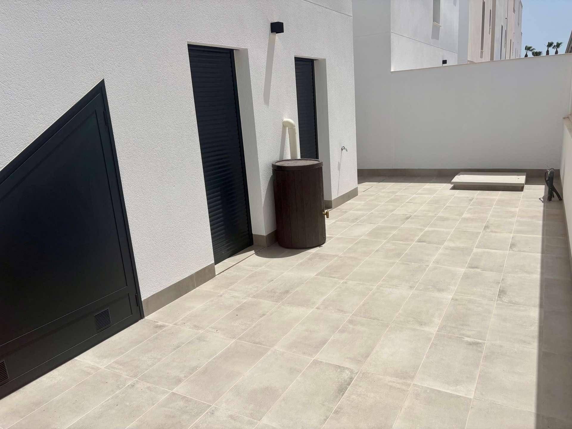Gefliester Außenbereich mit Warmwasserbereiter und zwei Türen mit Rollläden.