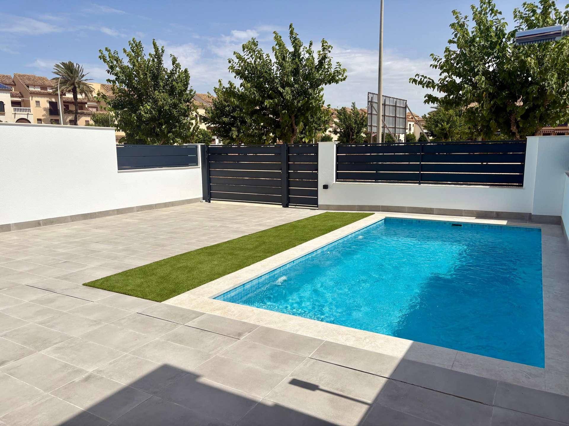 Privater Poolbereich mit Fliesenboden und Kunstrasen, umgeben von einer modernen Zaunanlage.
