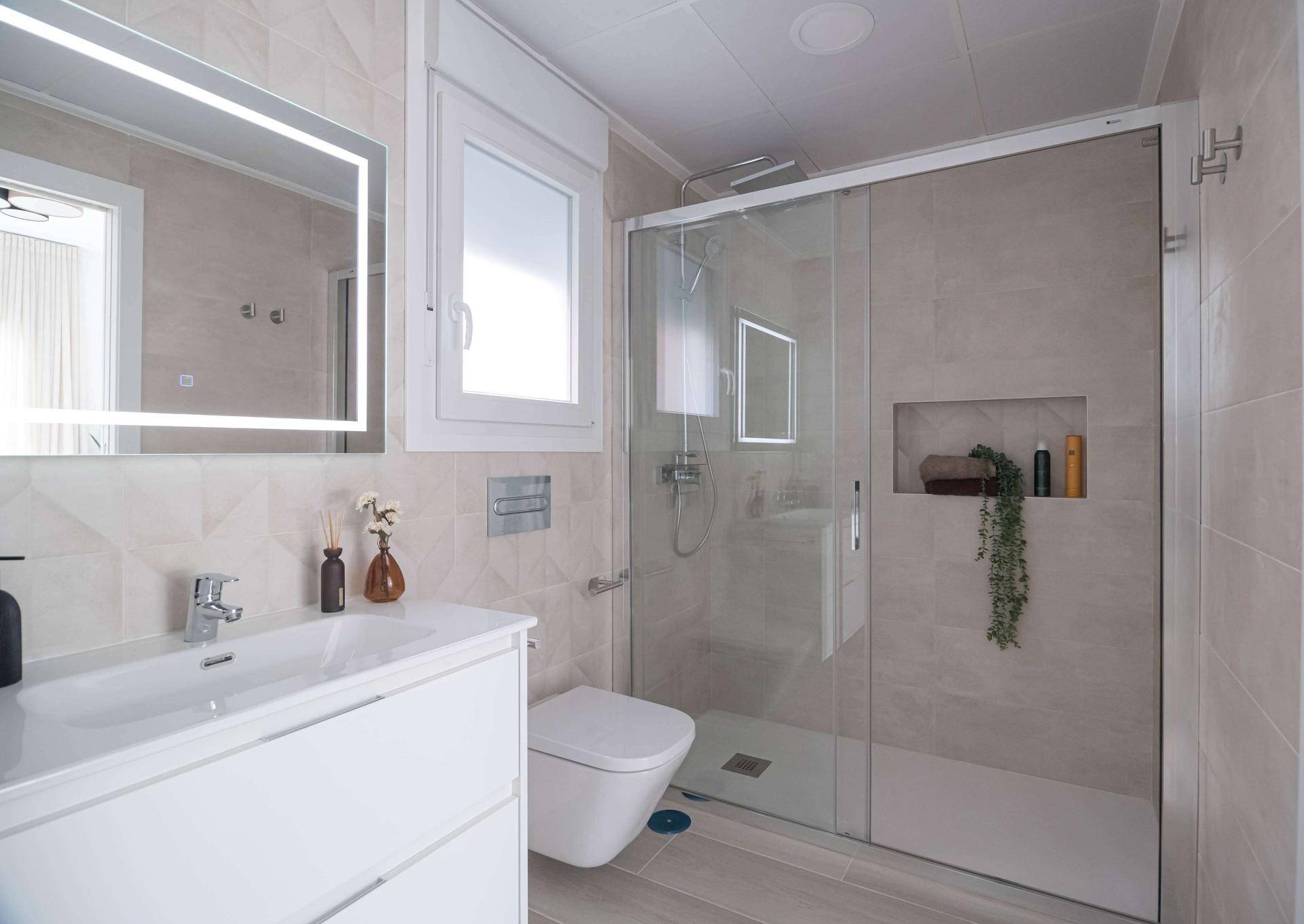 Modernes Badezimmer mit ebenerdiger Dusche, Waschtisch und Fenster für Tageslicht.