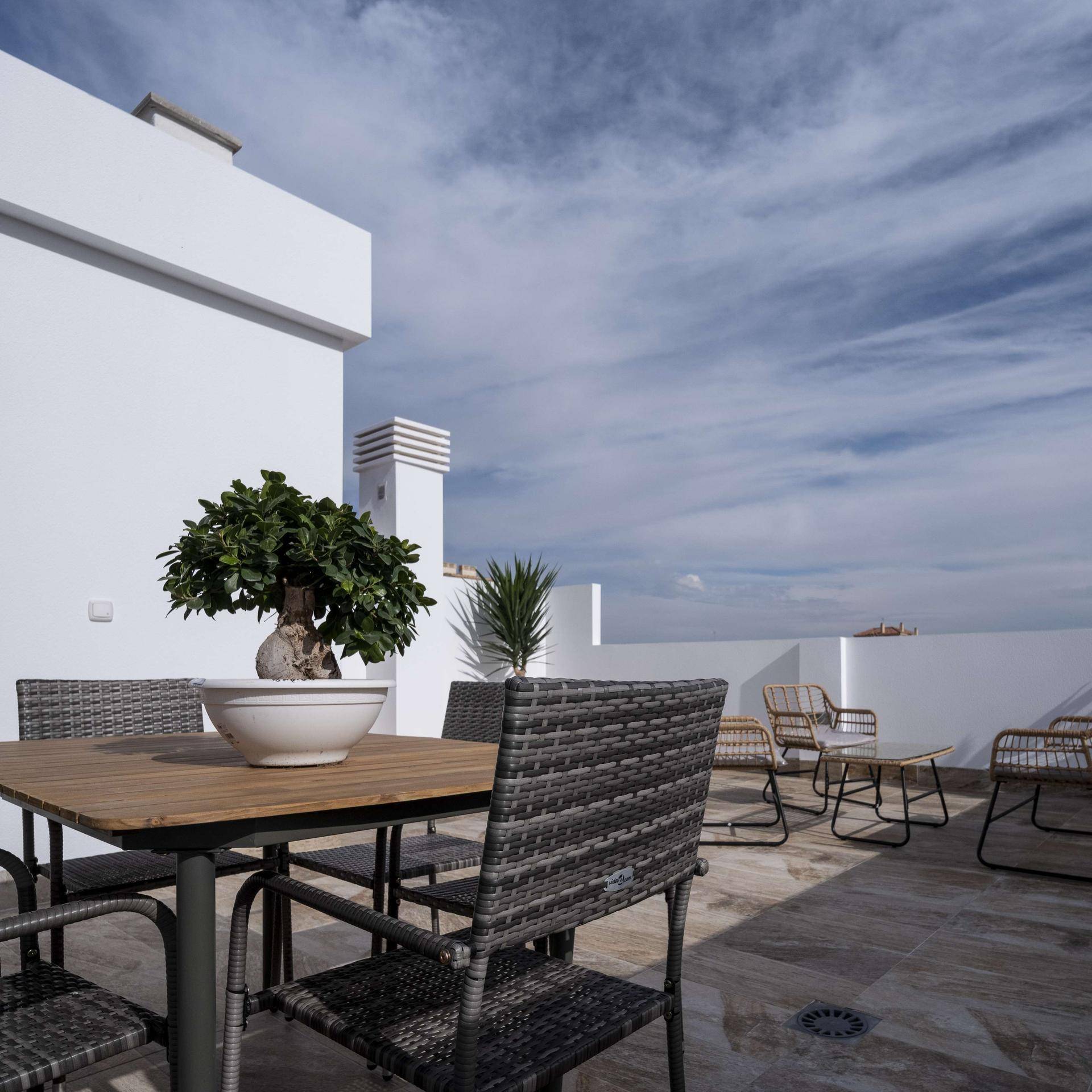 Großzügige Dachterrasse mit Essbereich und Lounge-Möbeln unter weitem Himmel.