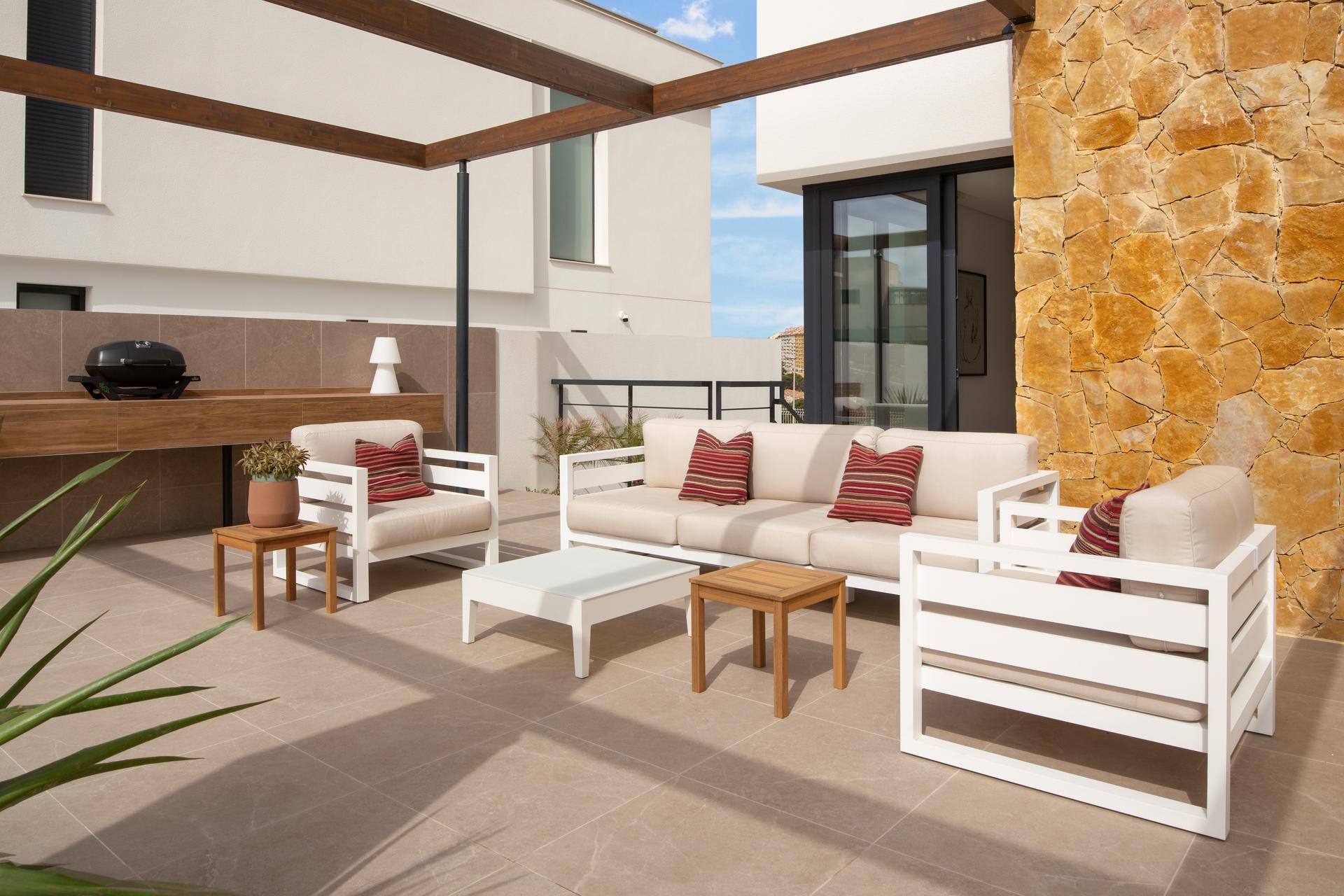 Gemütlicher Lounge-Bereich auf der Terrasse mit bequemen Sofas und einem Grill für gesellige Abende.