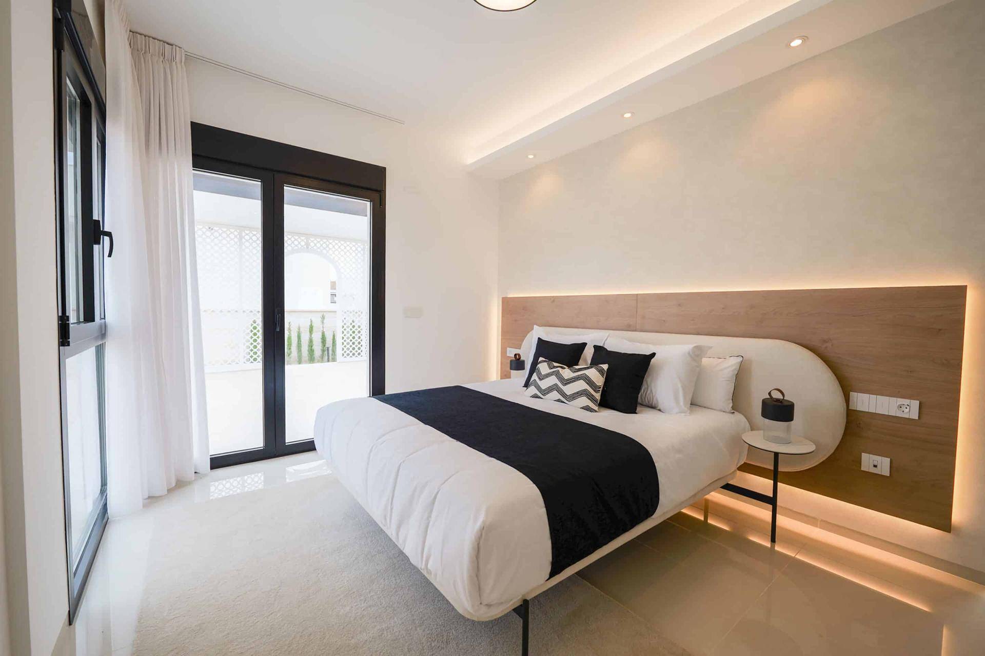 Helles Schlafzimmer mit Zugang zu einem Balkon und moderner Einrichtung.