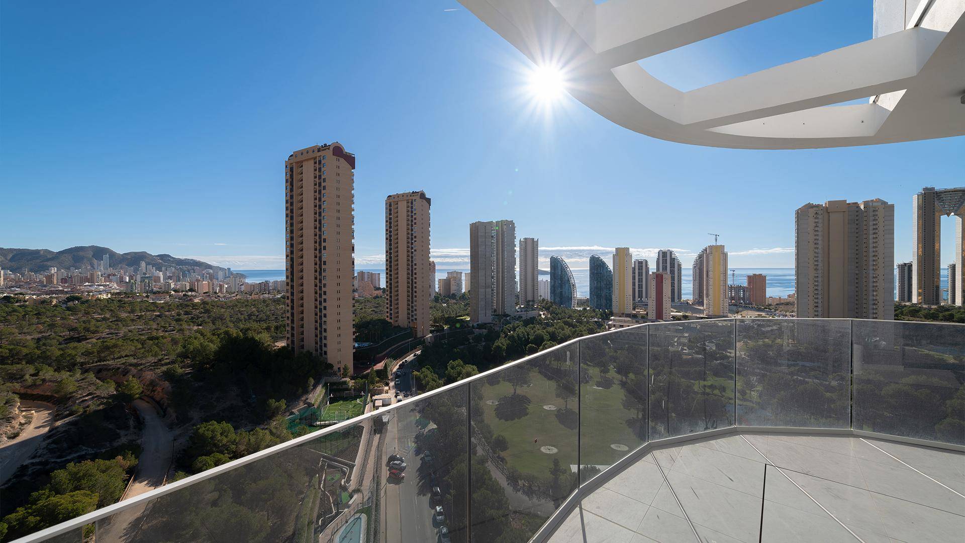 Panoramablick auf die Stadt und das Meer von einer hohen Terrasse unter strahlendem Sonnenschein.