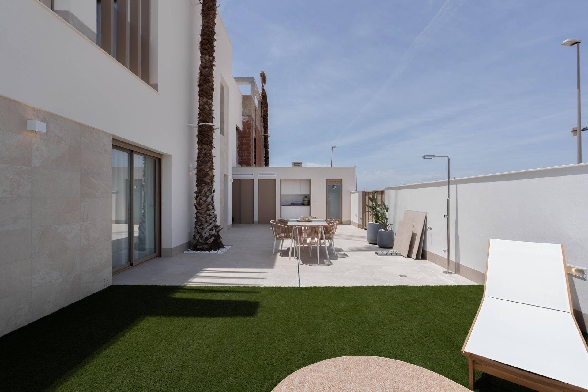 Gepflegter Gartenbereich mit Kunstrasen, Essbereich und privatem Pool im Hintergrund.