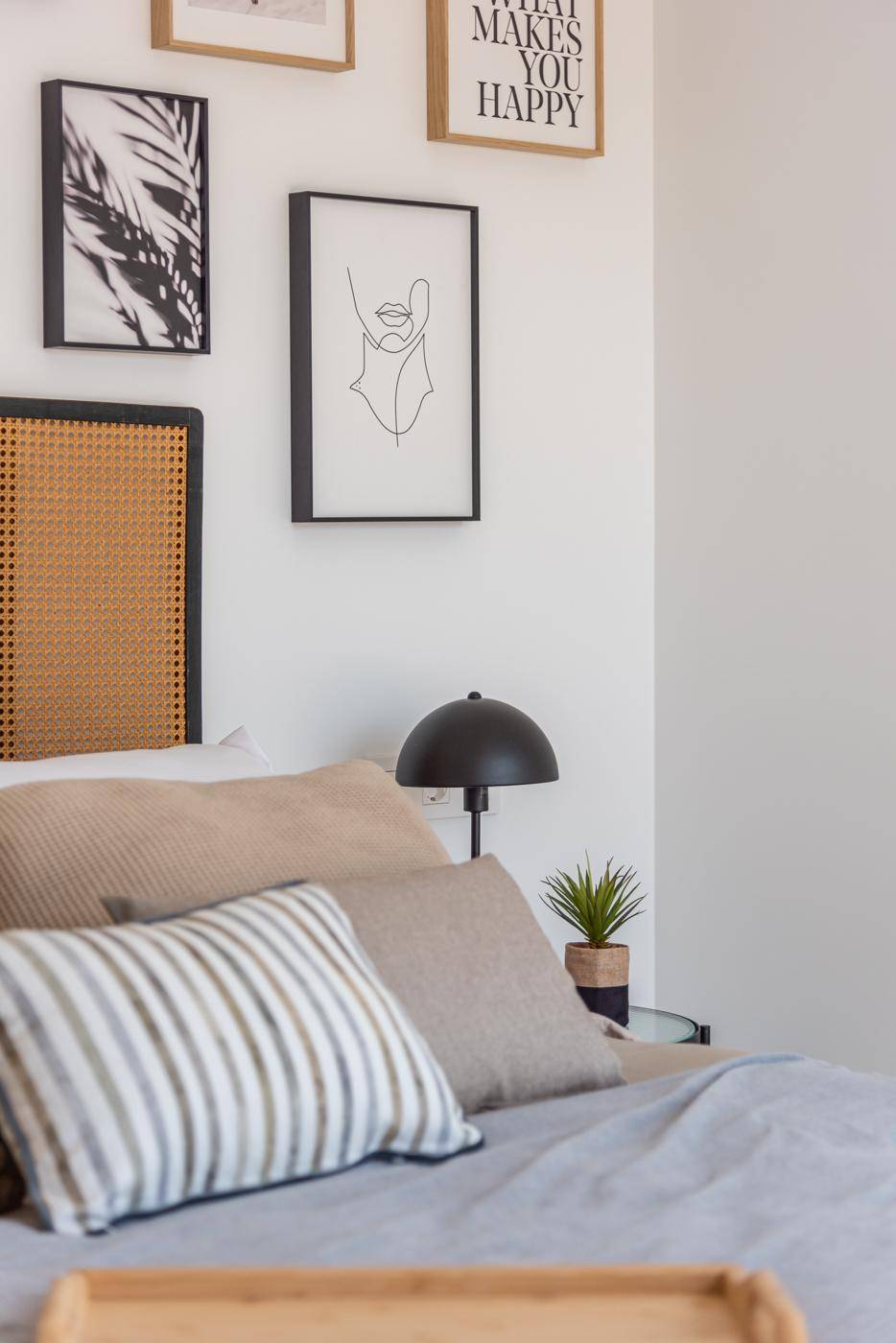 Detailansicht des Schlafzimmers mit Kissen, Nachttisch und gerahmten Bildern an der Wand.