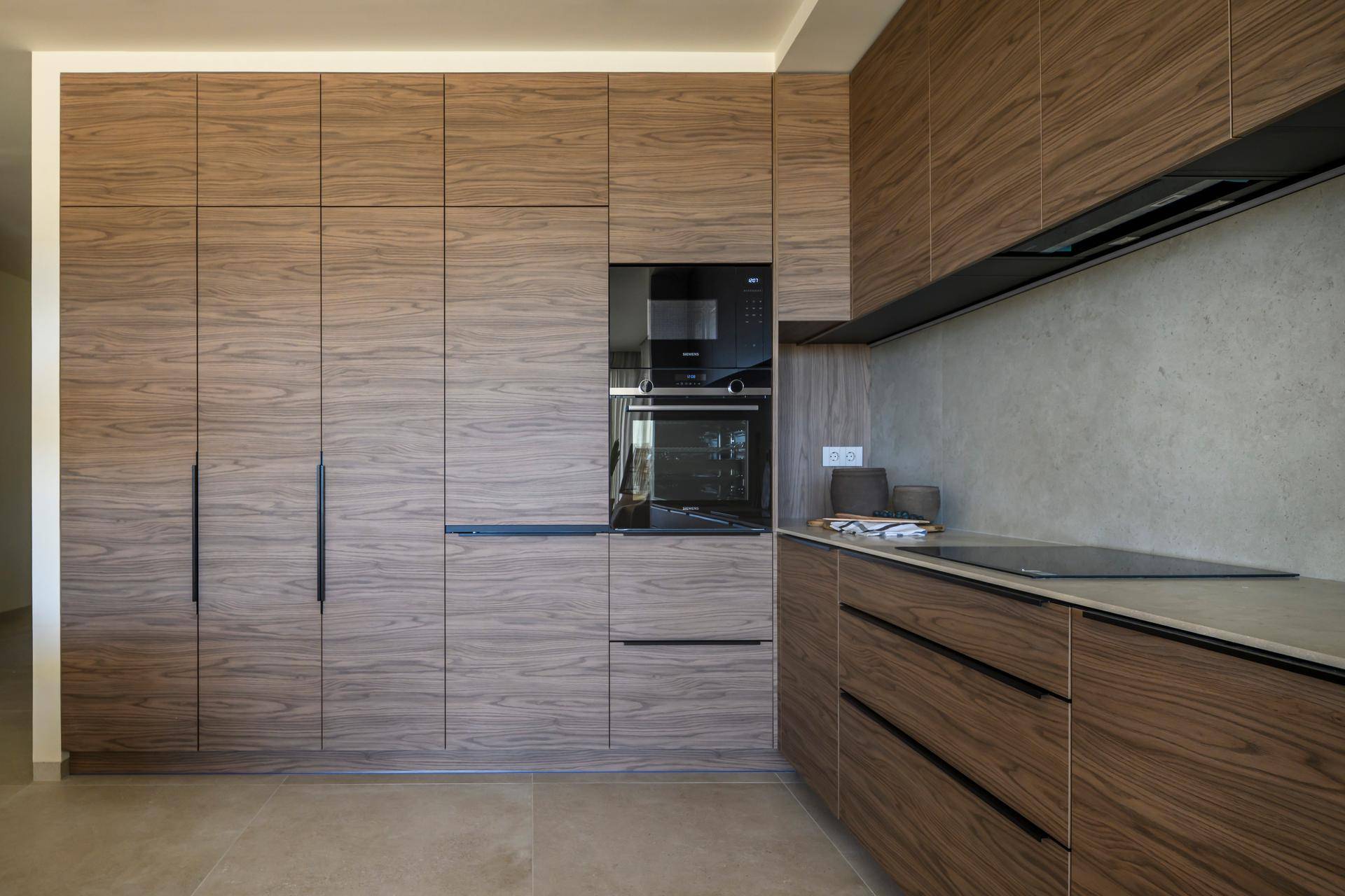 Moderne Küche mit dunklen Holzfronten, integrierten Geräten und Induktionskochfeld.