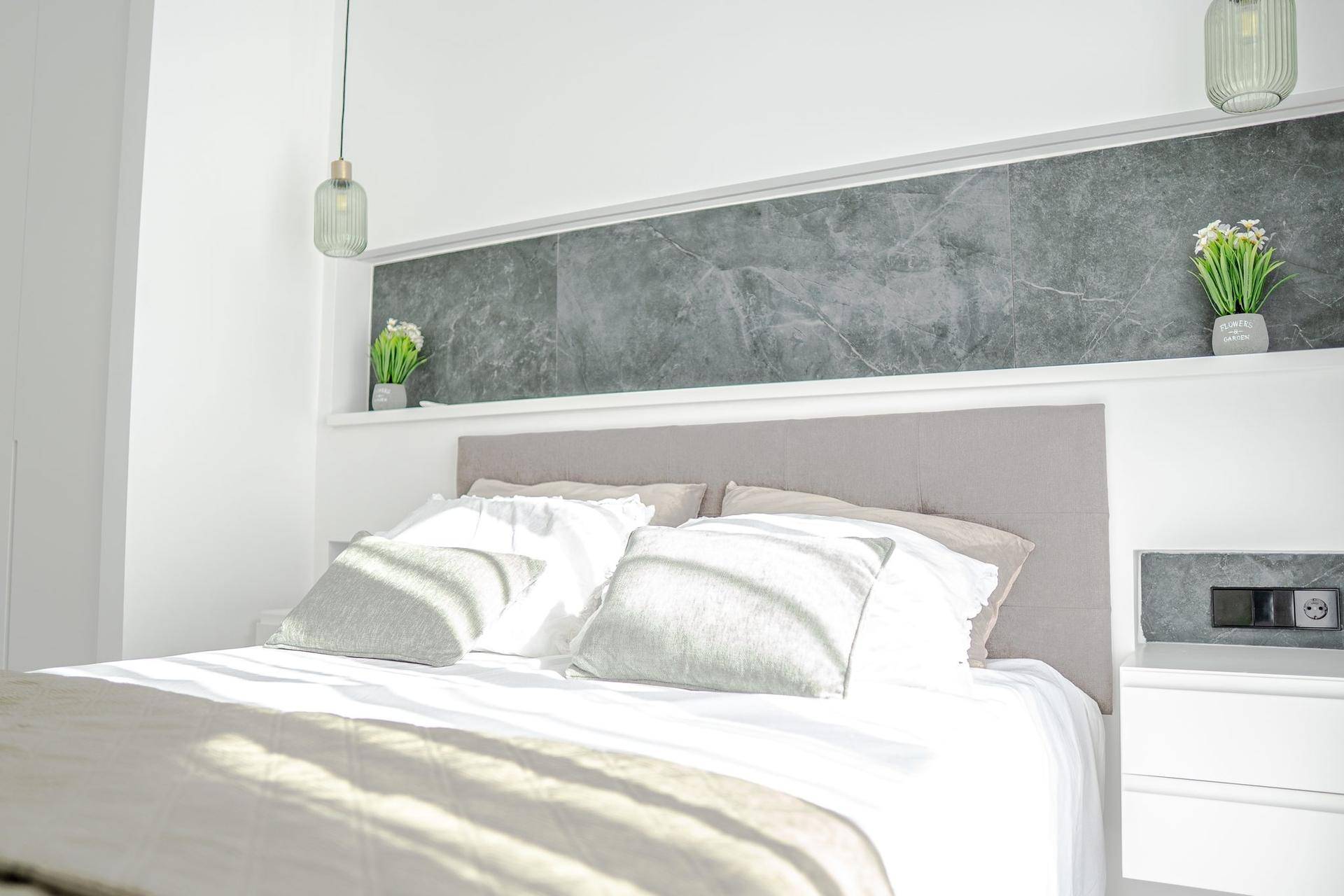 Helles Schlafzimmer mit modernem Bett, stilvoller Wanddekoration und viel natürlichem Licht.