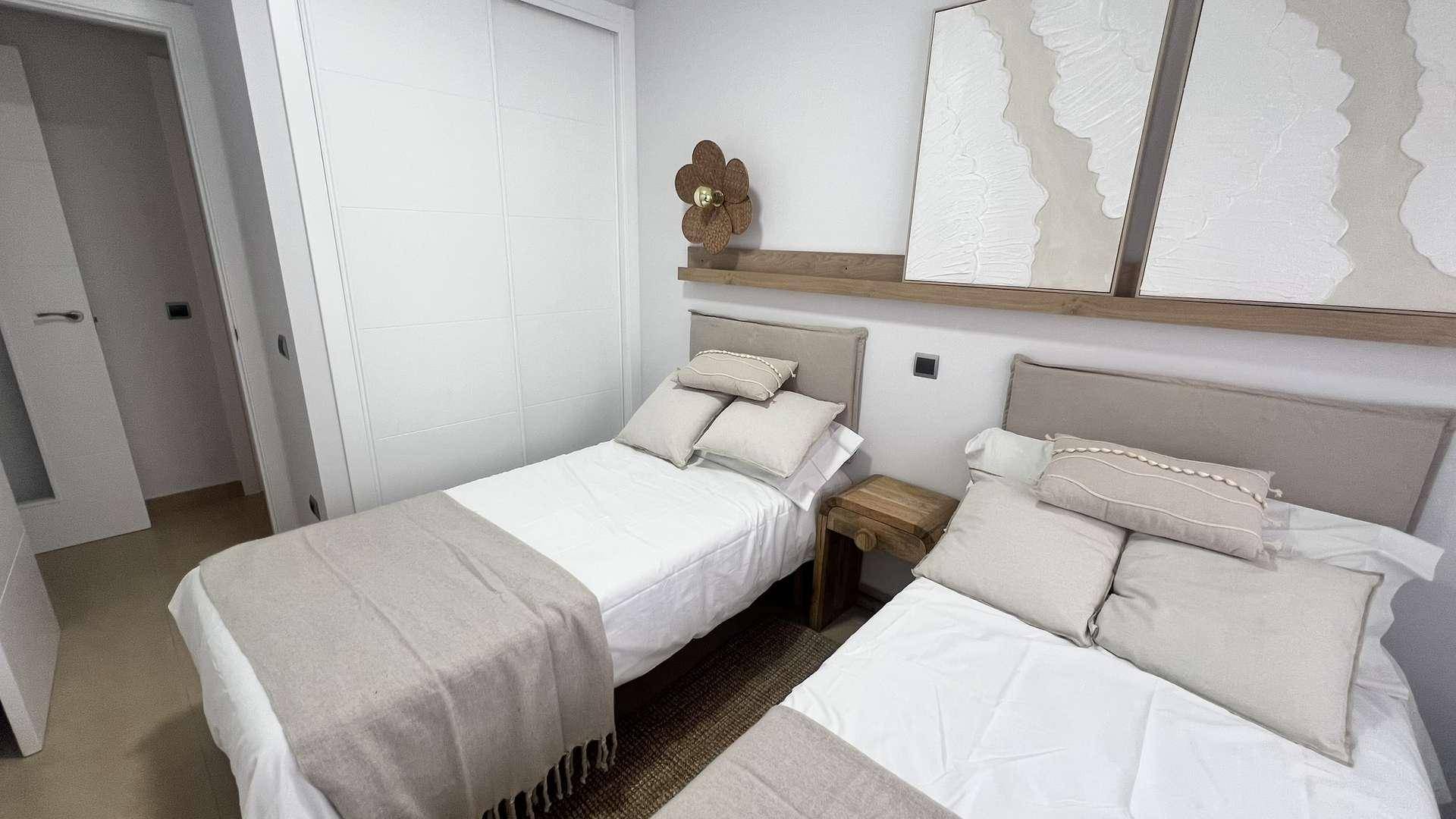Schlafzimmer mit zwei Einzelbetten, Einbauschrank und schlichter, moderner Dekoration.