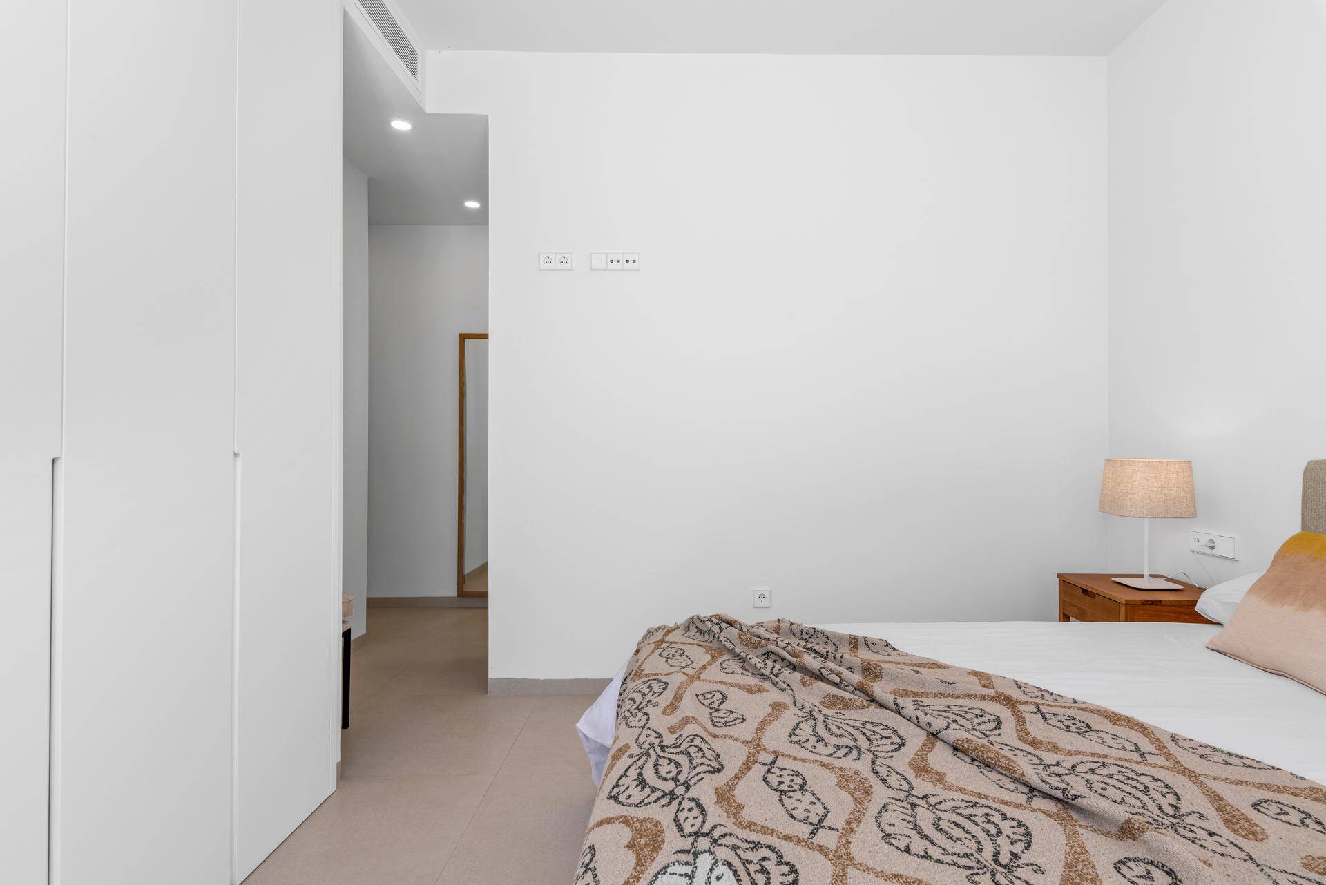 Helles Schlafzimmer mit Einbauschränken, modernem Bett und Blick in den Flur.