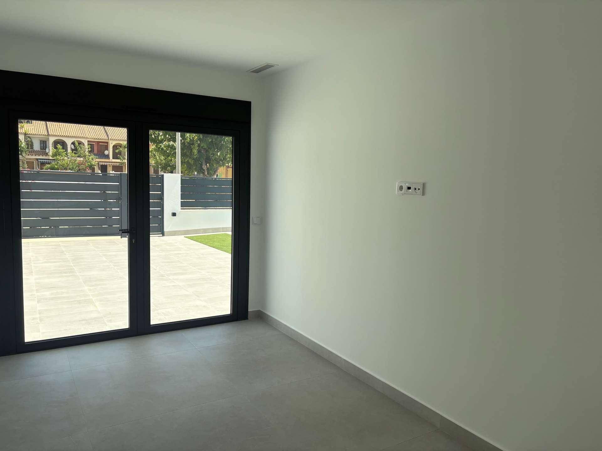 Geräumiger Raum mit Fliesenboden und Zugang zu einem privaten Außenbereich mit Kunstrasen.
