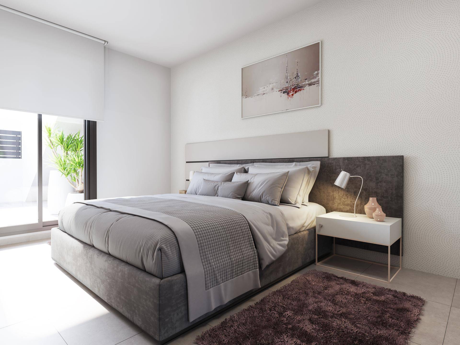 Helles Schlafzimmer mit modernem Bett, Nachttisch und direktem Zugang zu einem Außenbereich.