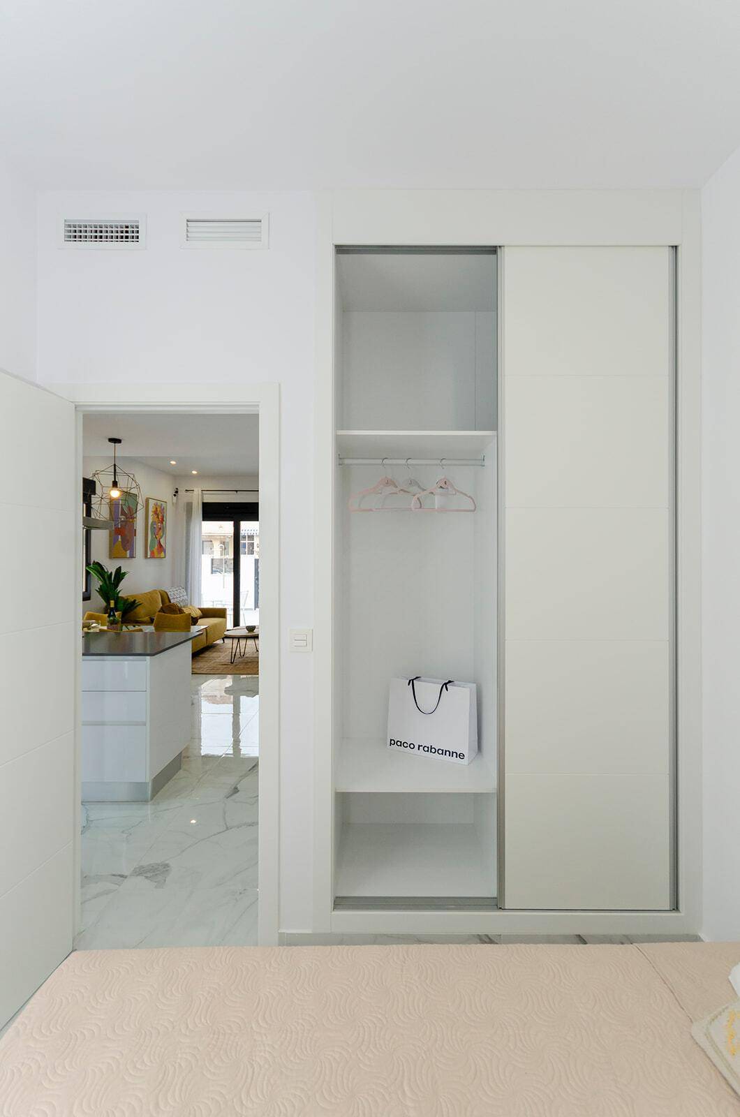 Helles Schlafzimmer mit integriertem Kleiderschrank und Blick in den Wohnbereich.