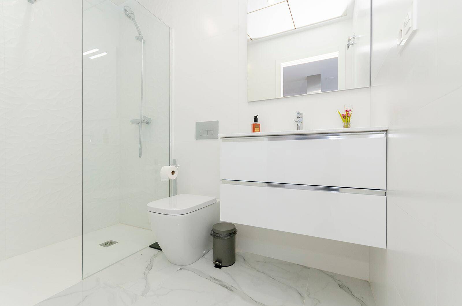 Modernes Badezimmer mit begehbarer Dusche, wandhängendem WC und elegantem Waschtisch.