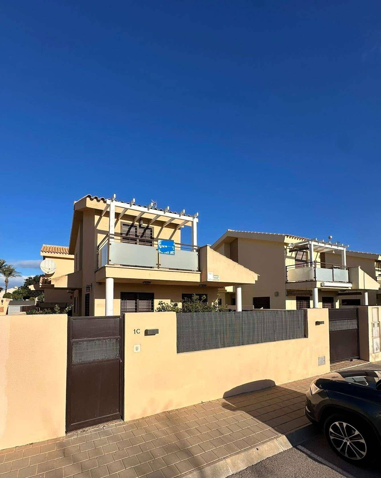 Vorderansicht eines modernen Reihenhauses mit Balkon, Pergola und einer 'Vende'-Tafel.