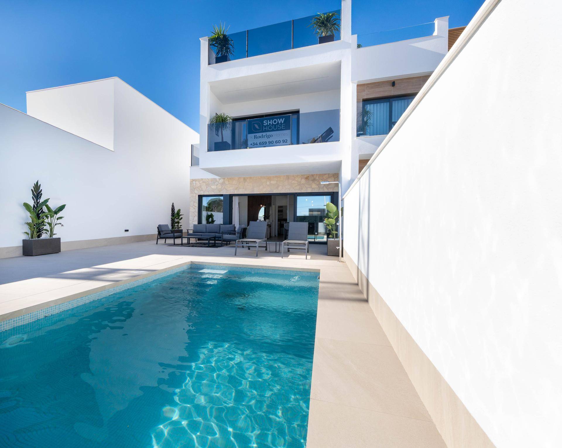 Privater Poolbereich mit klarem Wasser und heller Terrasse, umgeben von weißen Mauern.