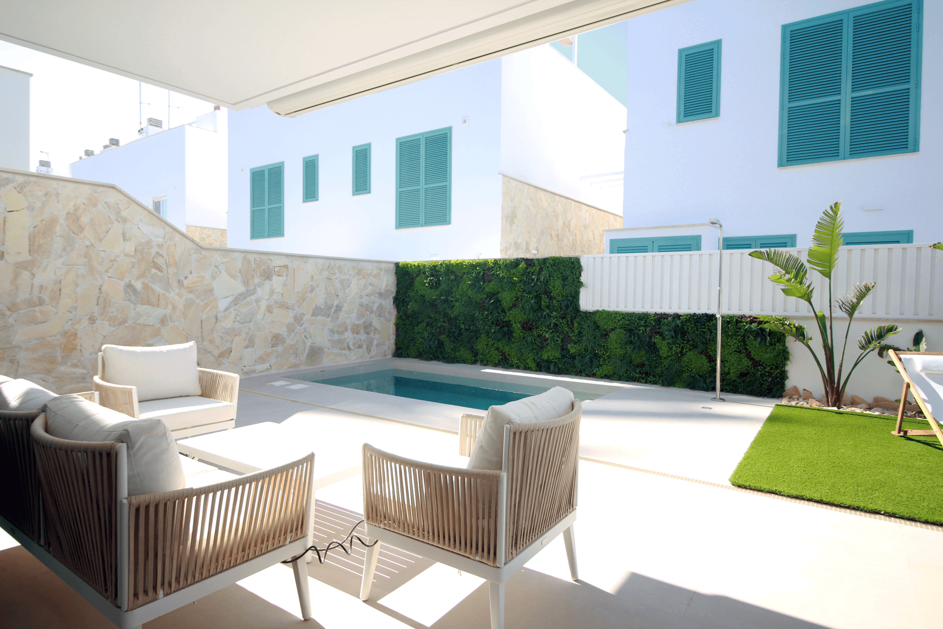 Helle Terrasse mit kleinem Pool, bequemen Lounge-Möbeln und vertikalem Garten an der Wand.