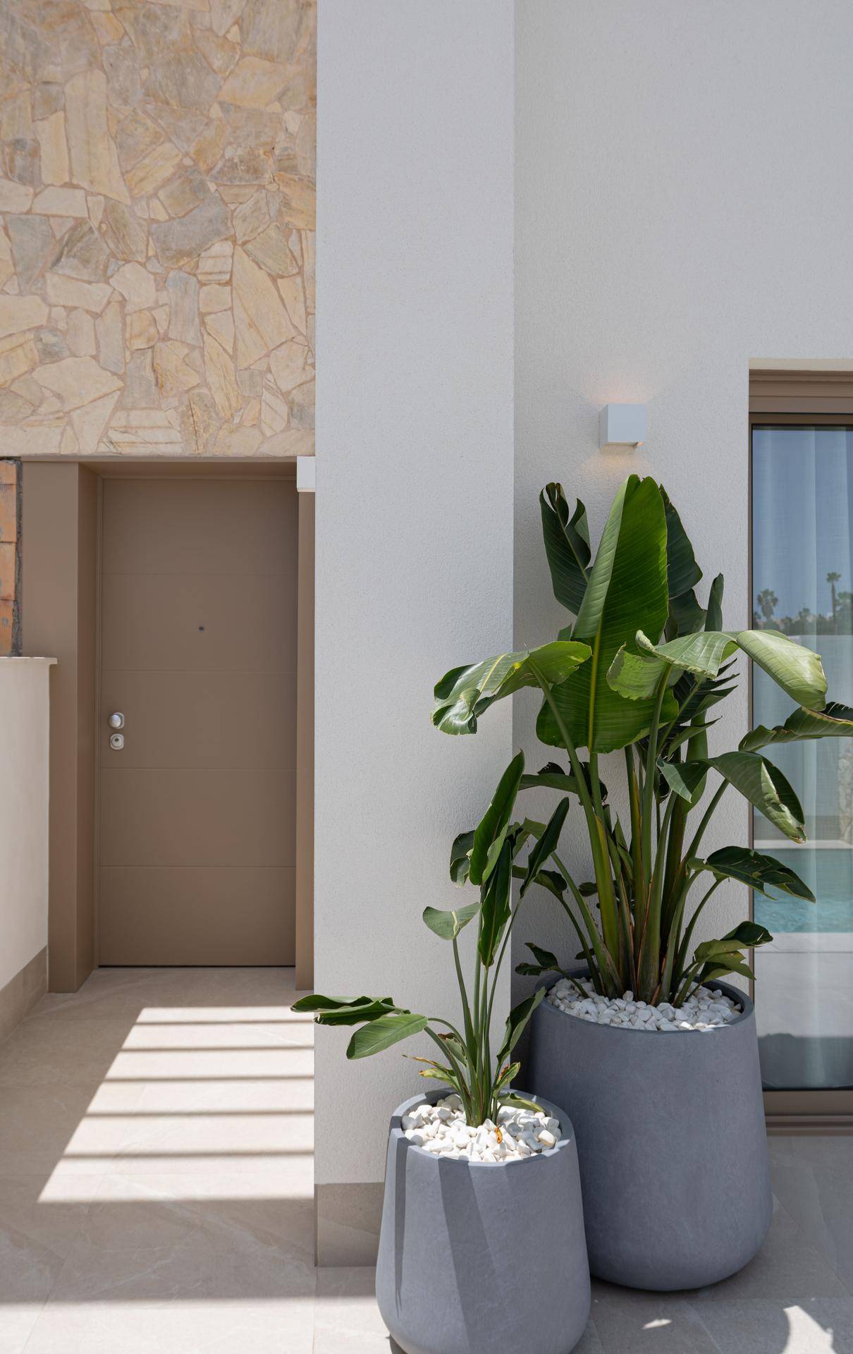 Moderner Eingangsbereich einer Villa mit dekorativen Pflanzen und Natursteinverkleidung.