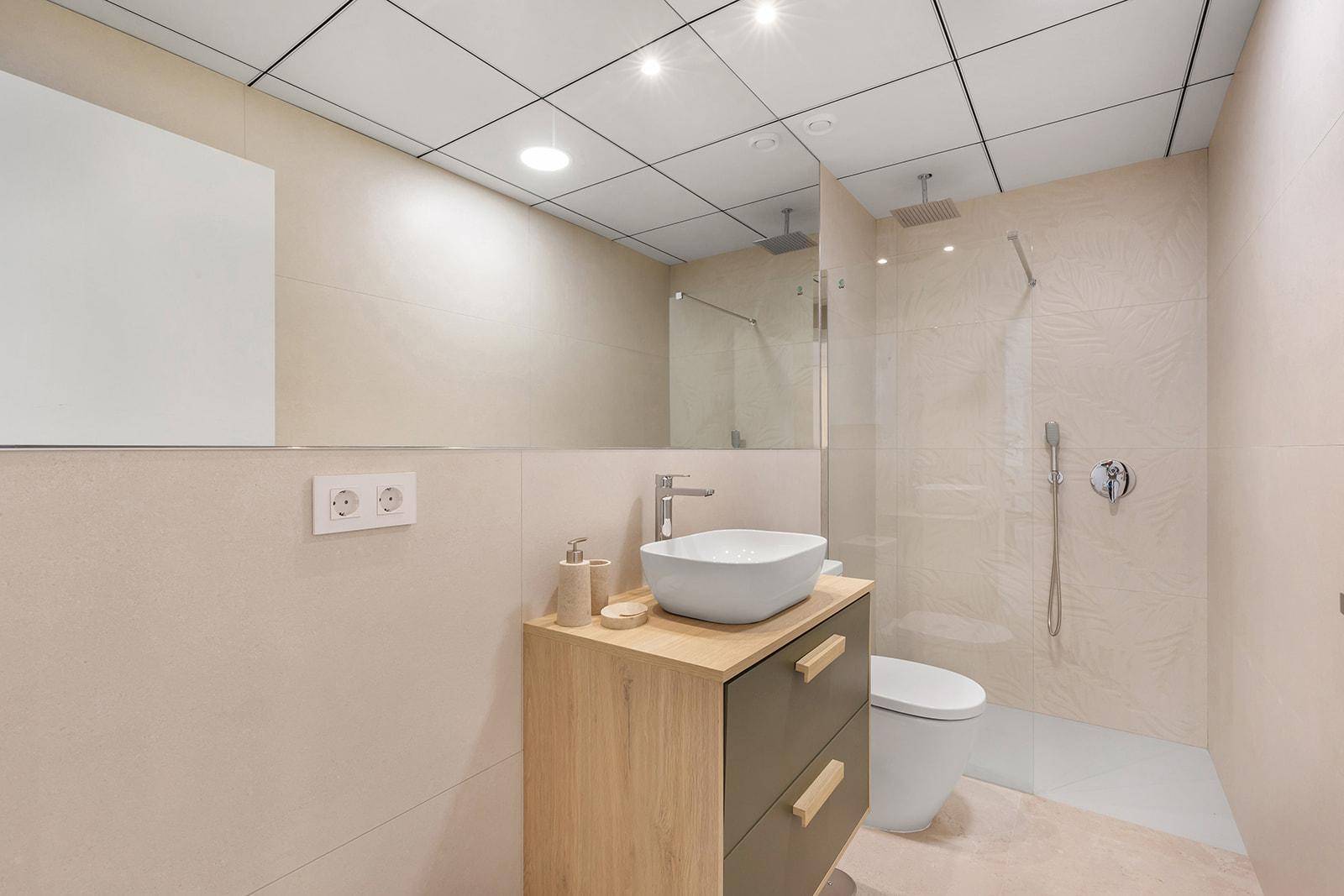Zeitgemäßes Badezimmer mit Aufsatzwaschbecken, großer Spiegelfläche und begehbarer Dusche.