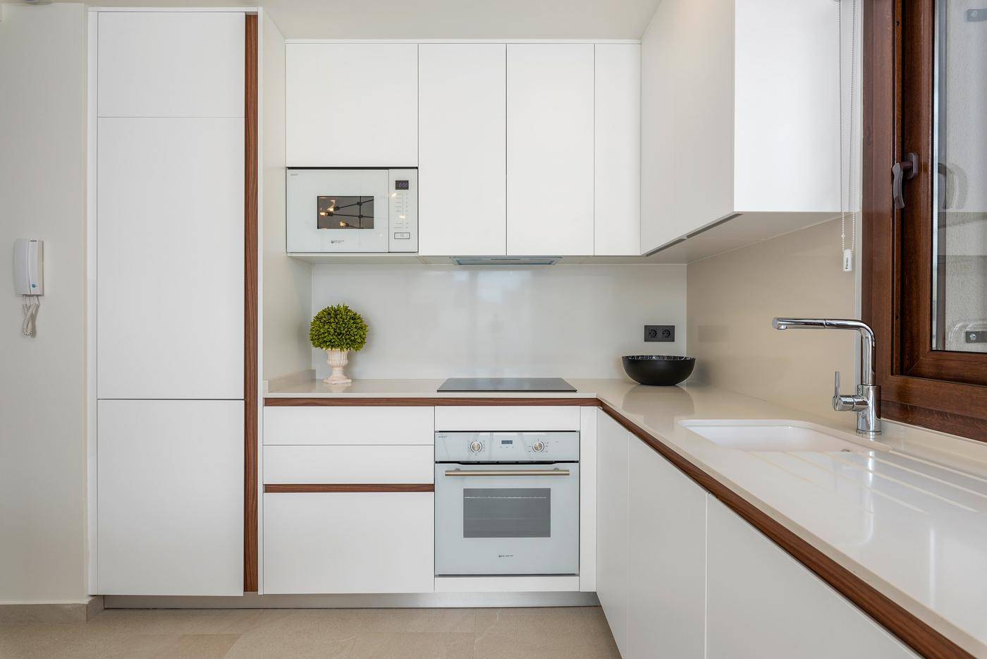 Detailansicht der modernen Einbauküche mit weißen Schränken, integriertem Backofen und Mikrowelle.
