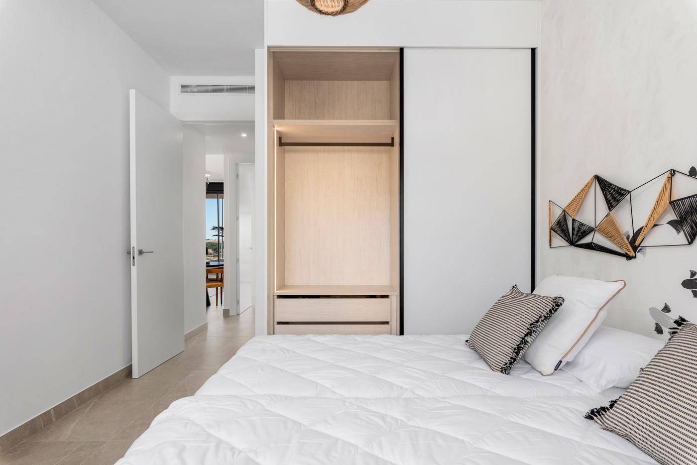 Schlafzimmer mit offenem Einbauschrank, Doppelbett und kreativer Wandgestaltung.