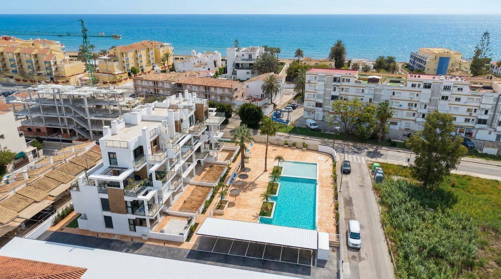 Luftaufnahme eines modernen Apartmentkomplexes mit Poolbereich nahe der Küste und dem Meer.