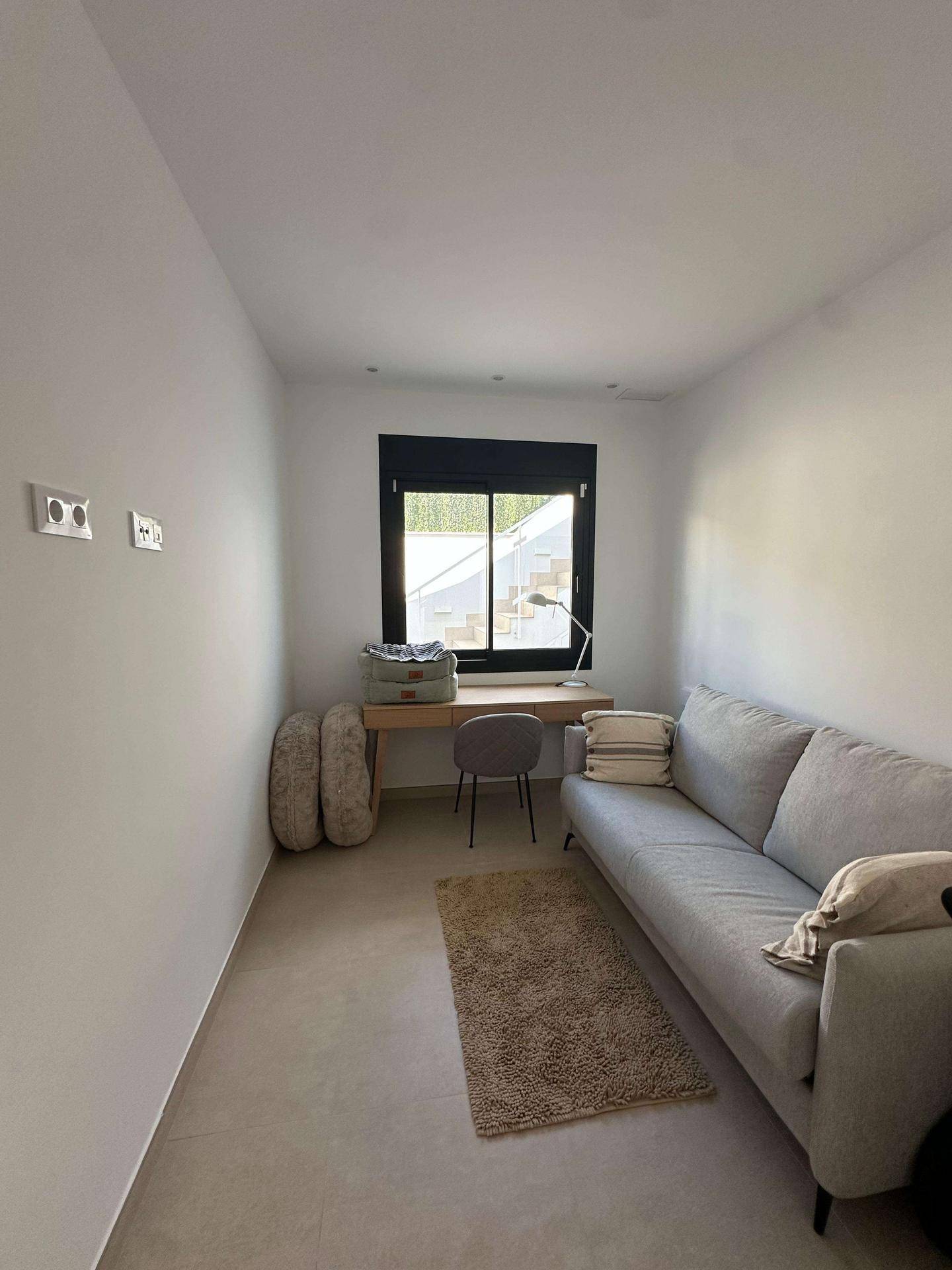 Kleiner Raum mit Sofa, Schreibtisch und Fenster, ideal als Büro oder Gästezimmer.