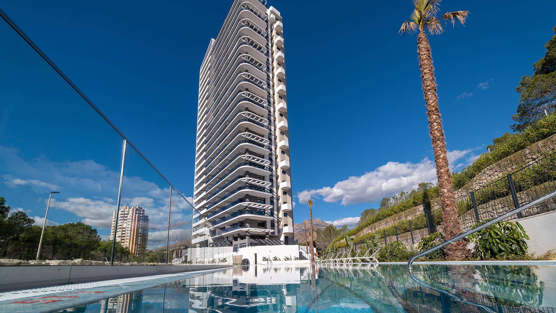 Beeindruckendes Hochhaus mit eleganten Balkonen und einem großen, einladenden Swimmingpool.
