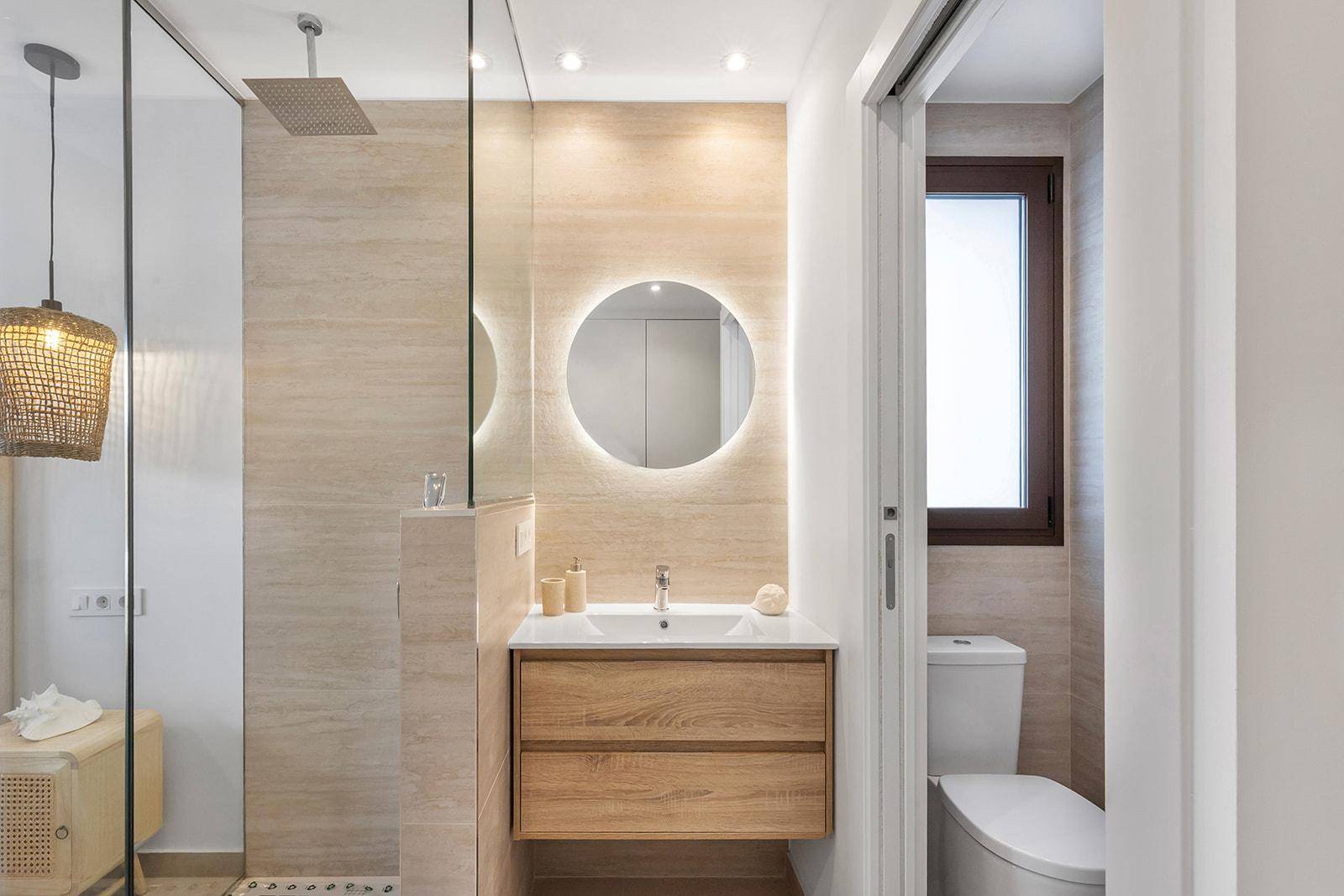 Modernes Badezimmer mit begehbarer Dusche, beleuchtetem Spiegel und Holzwaschtisch.