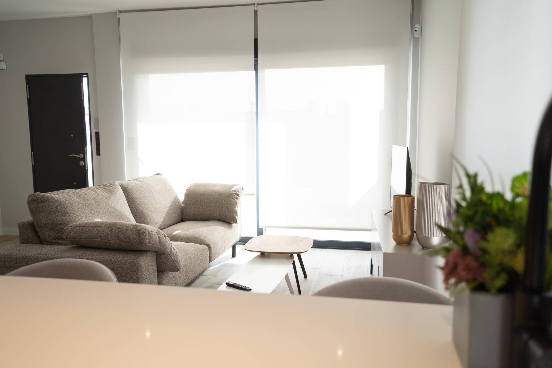 Helles Wohnzimmer mit beigem Sofa, Couchtisch und großen Fenstern.
