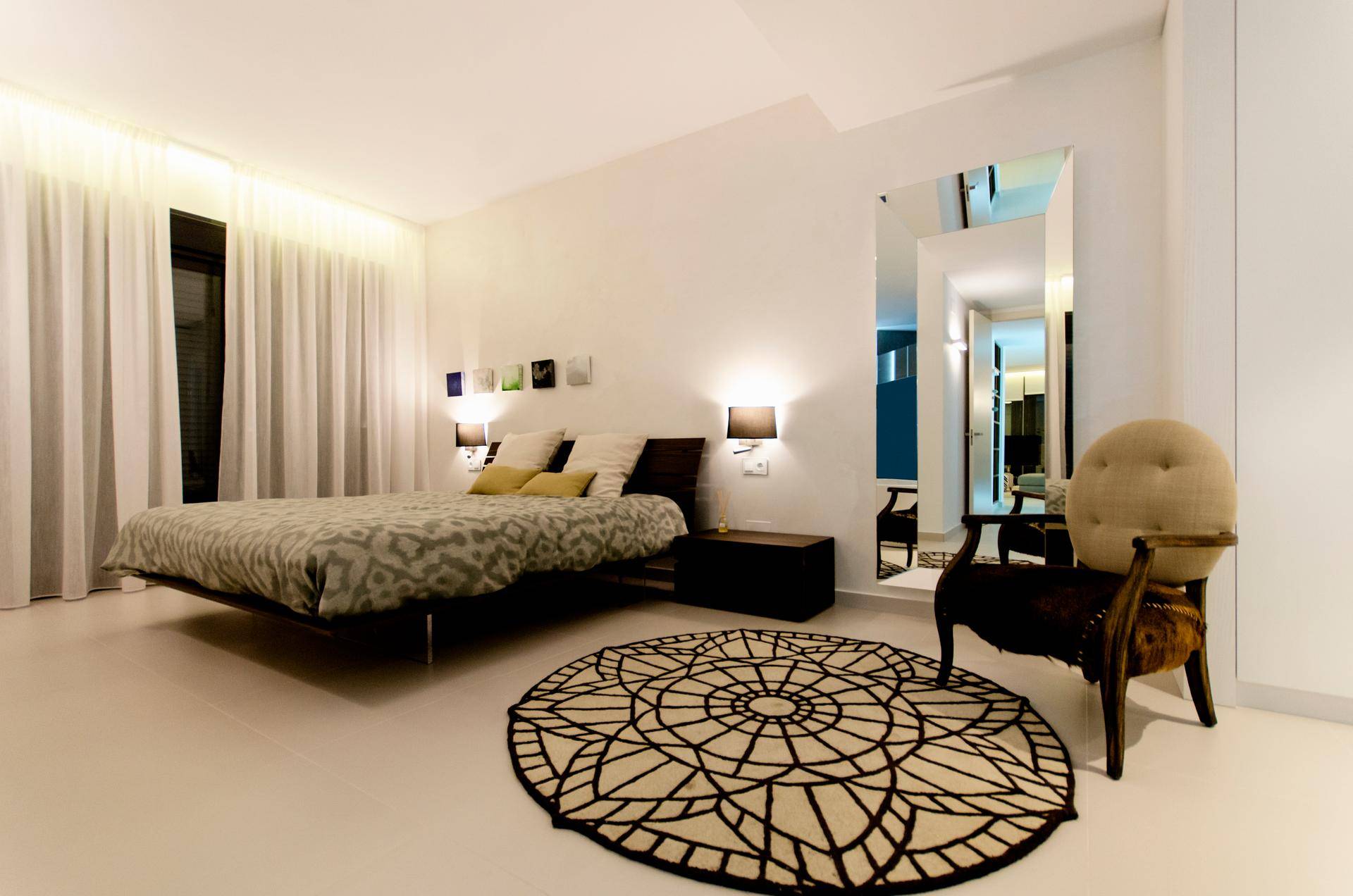 Geräumiges Schlafzimmer mit großem Bett, elegantem Teppich und indirekter Beleuchtung.