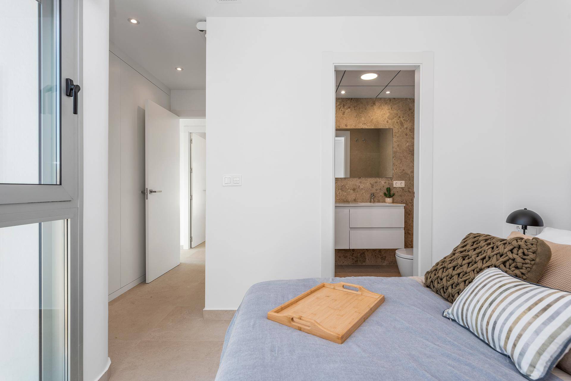Schlafzimmer mit Zugang zu einem Badezimmer, ausgestattet mit modernen Möbeln und hellem Ambiente.
