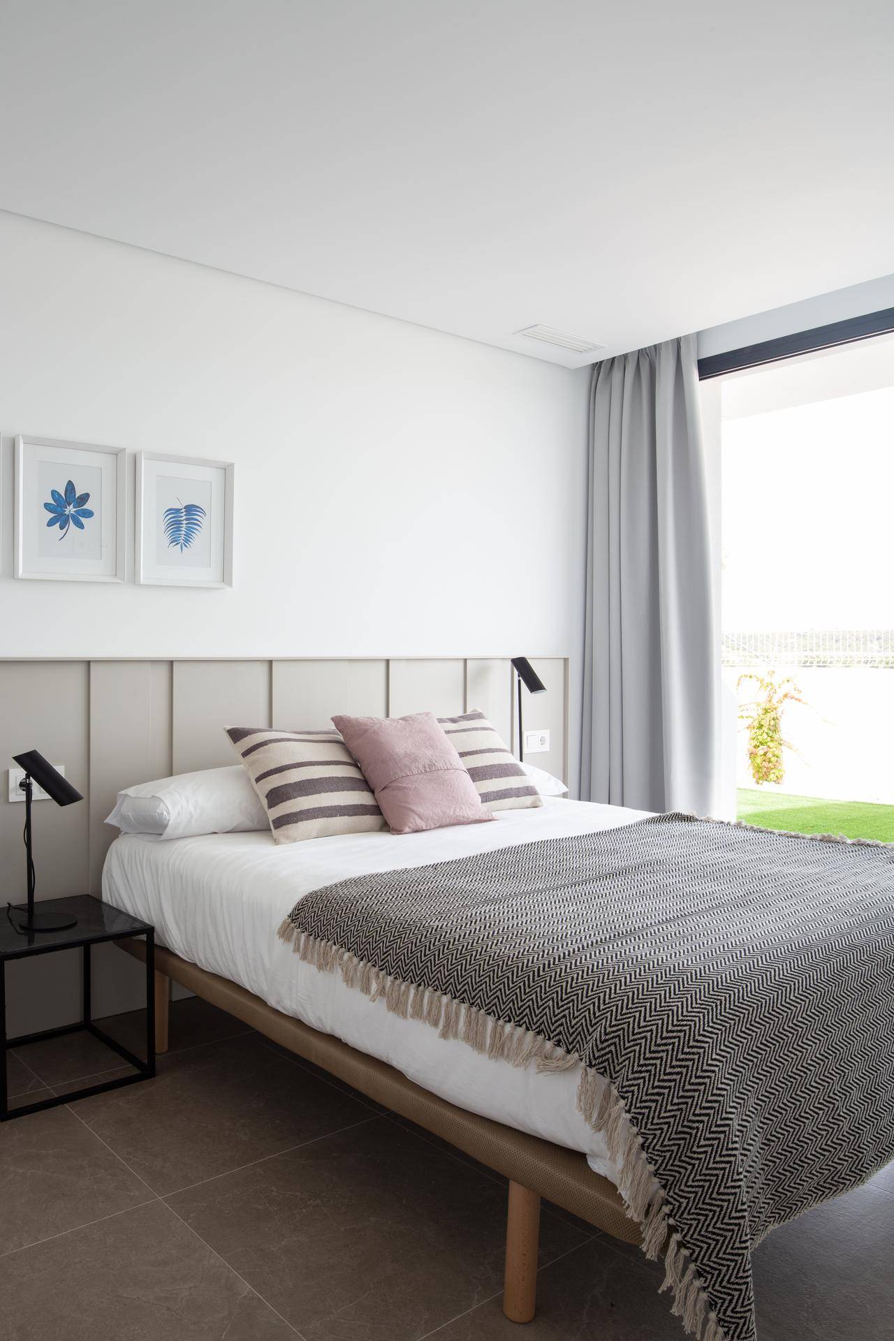 Modernes Schlafzimmer mit Doppelbett, Nachttischen und großem Fenster für viel Tageslicht.