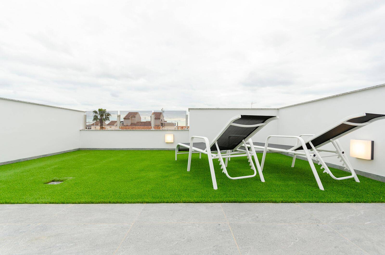 Entspannungsbereich auf der Dachterrasse mit Kunstrasen und bequemen Liegestühlen.