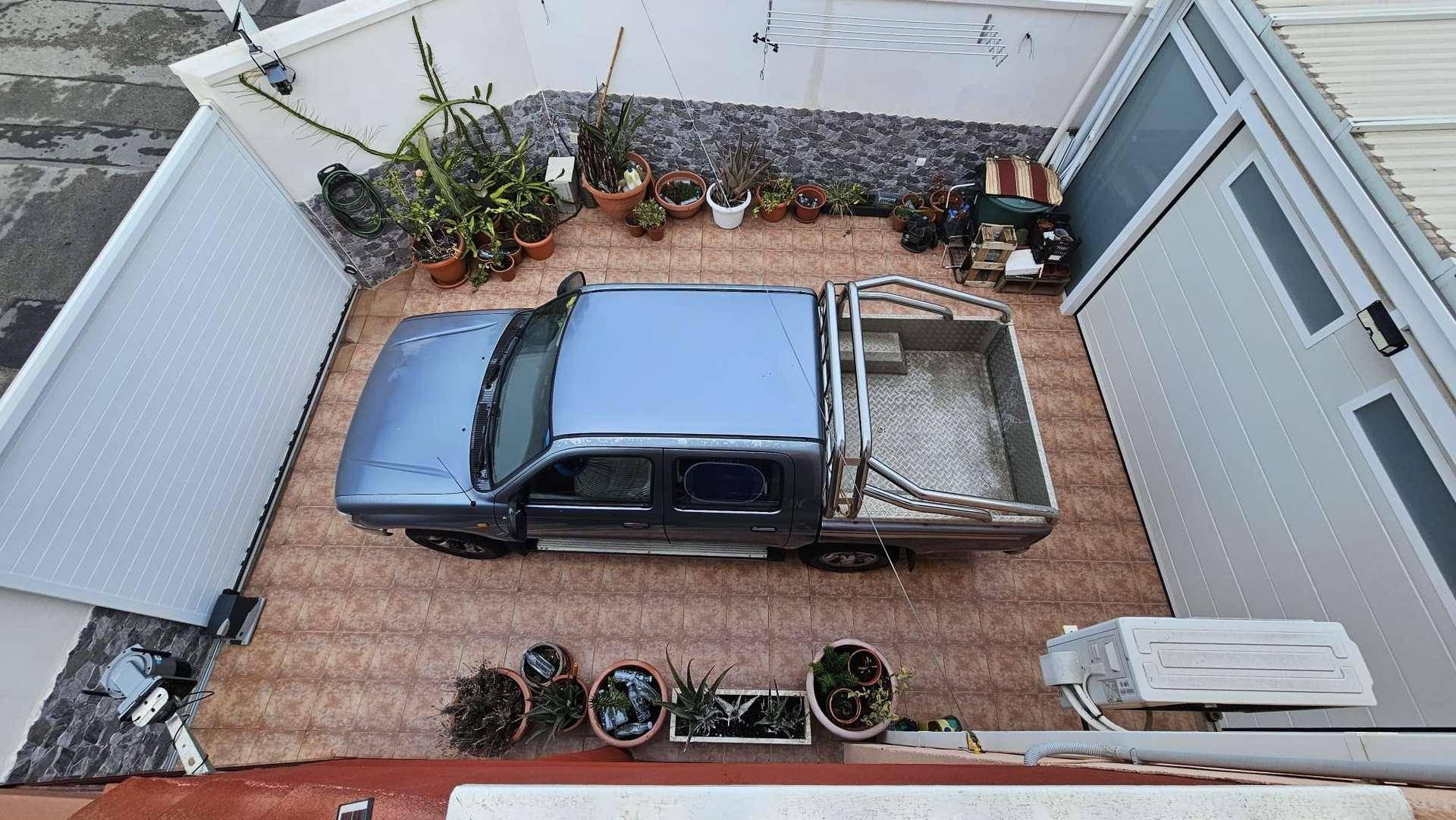 Geflieste Terrasse, die auch als Parkplatz dient, umgeben von Topfpflanzen.
