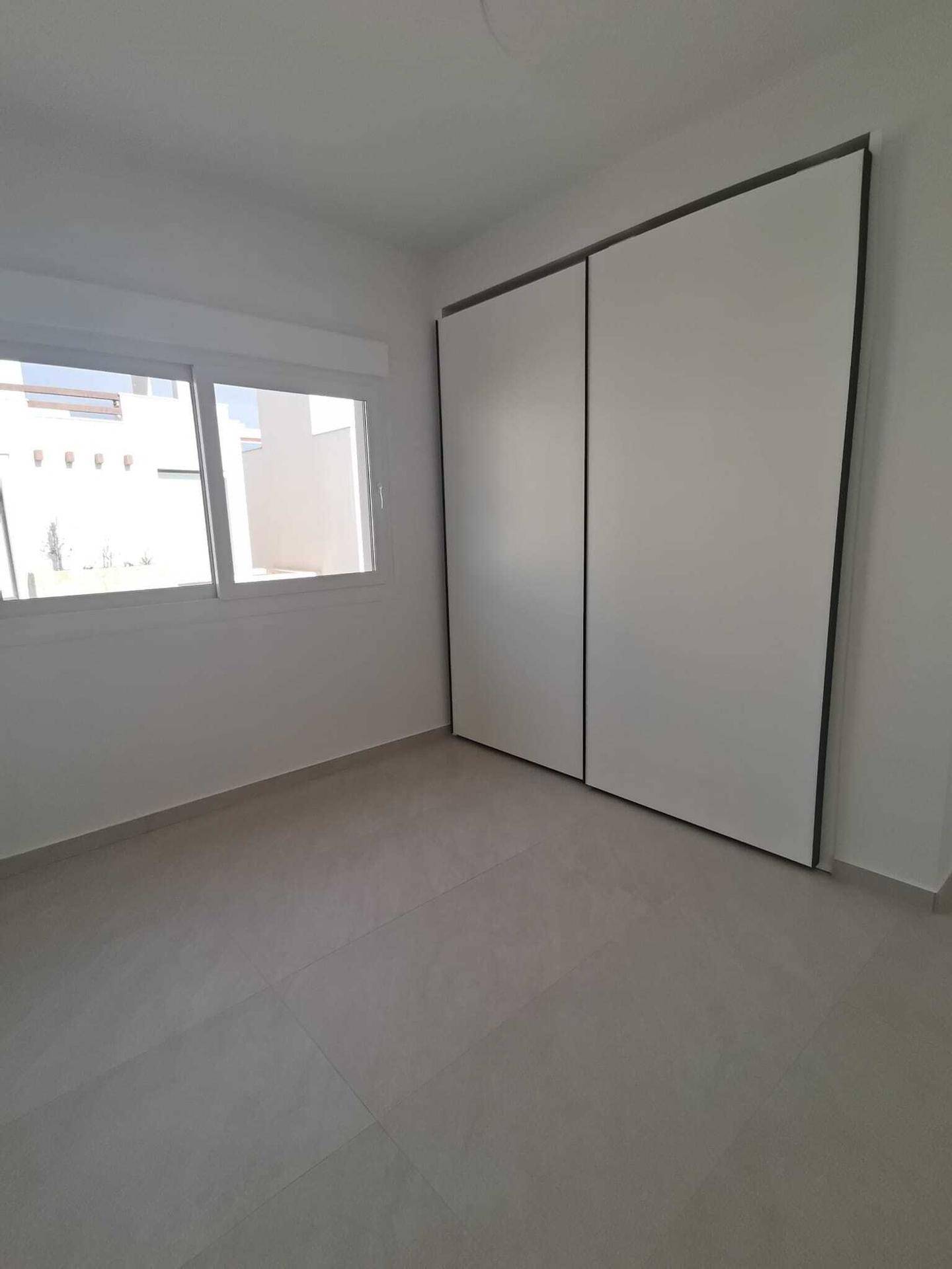 Helles Schlafzimmer mit Einbauschrank und Fenster, bereit zur individuellen Einrichtung und Gestaltung.