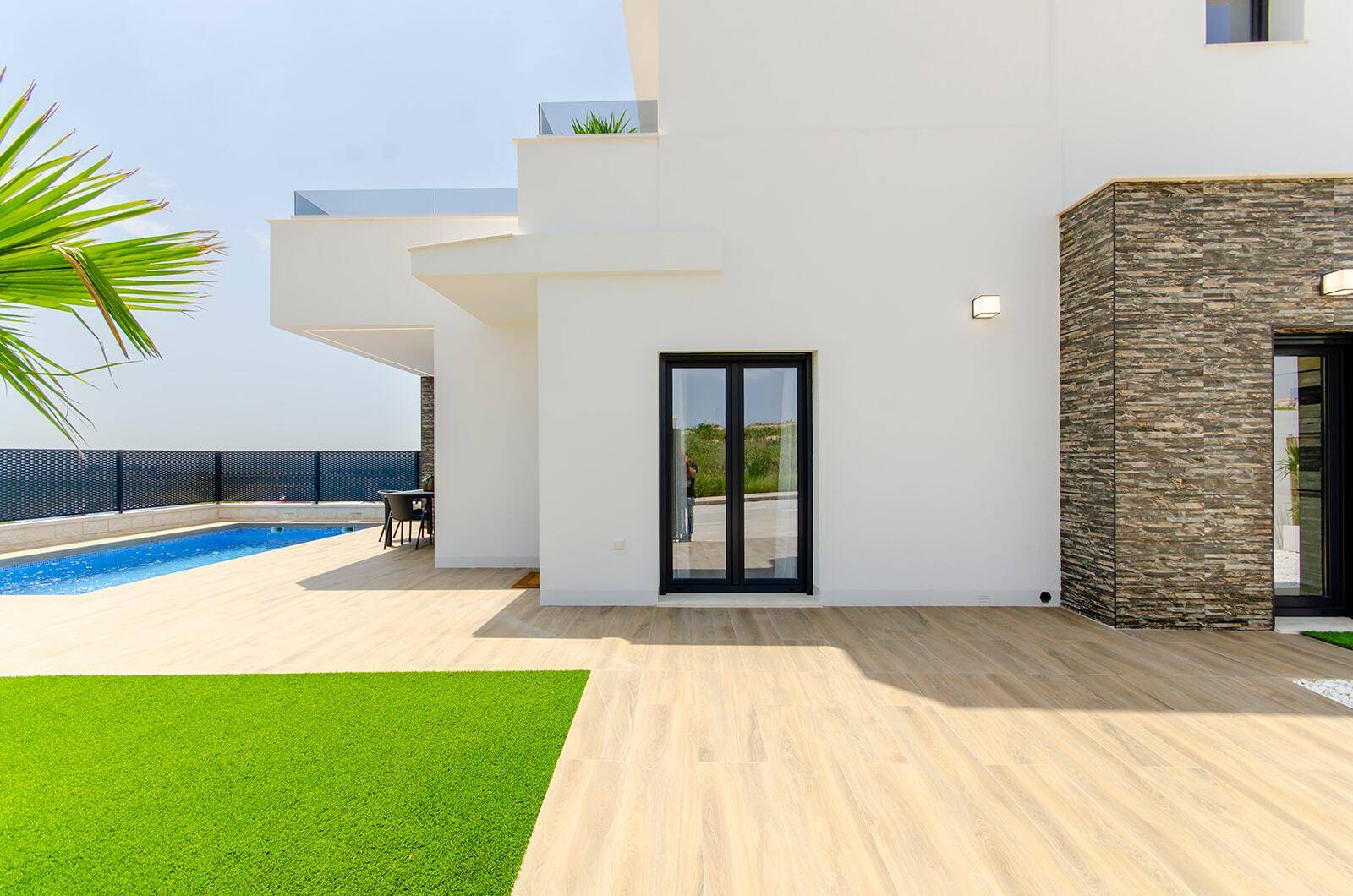 Heller Außenbereich mit Pool, großzügiger Terrasse und moderner Architektur der Villa.