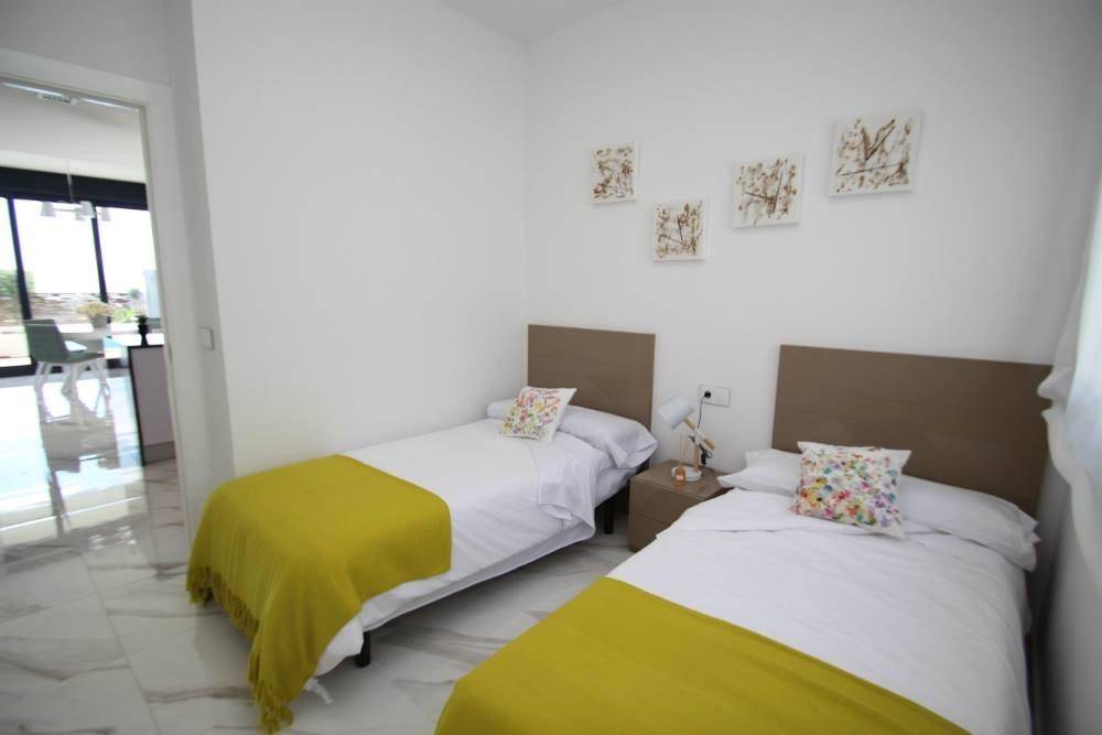 Helles Schlafzimmer mit zwei Einzelbetten, Marmorboden und moderner Dekoration.