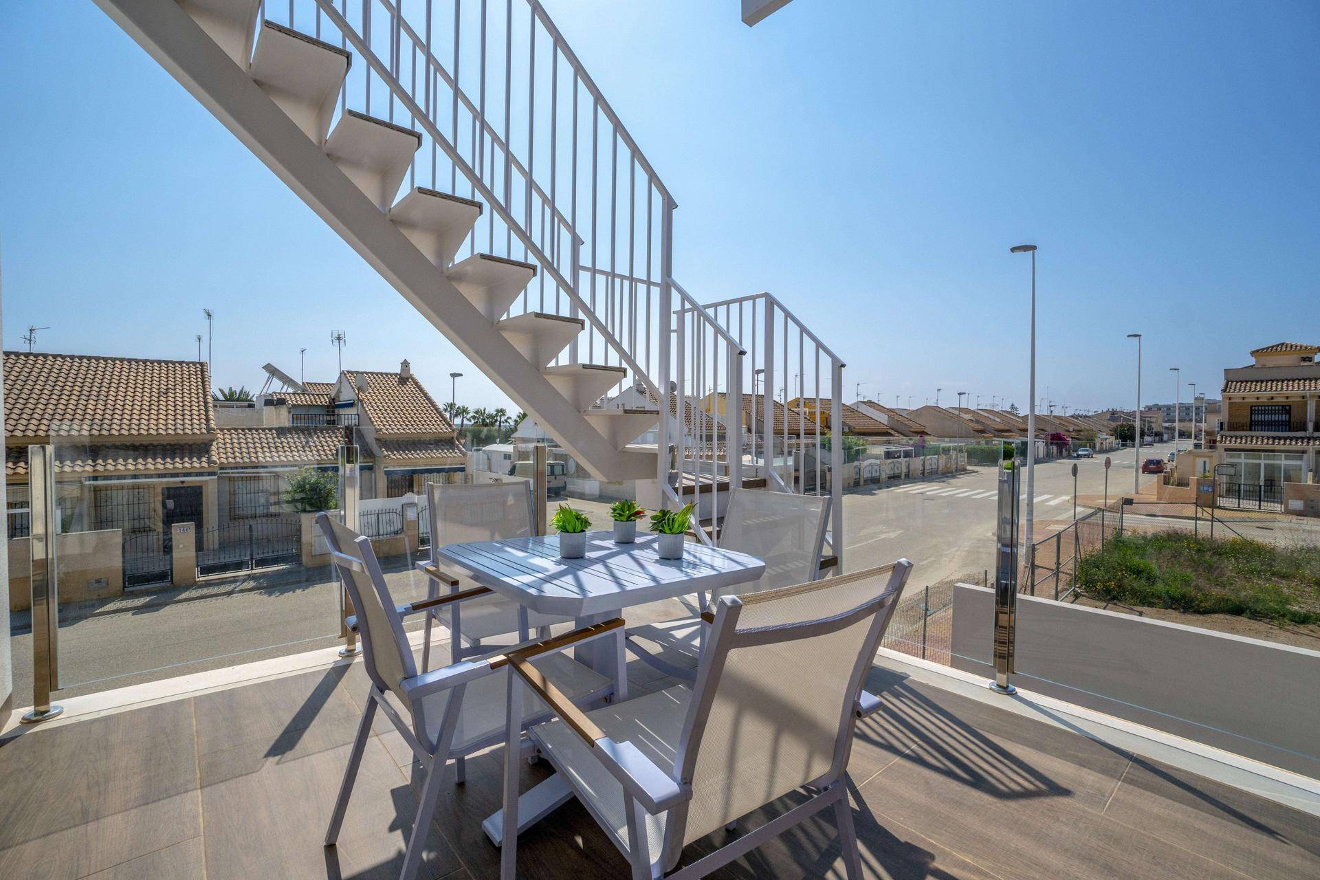 Heller Balkon mit Außentreppe und Blick auf die Straße und benachbarte Häuser.