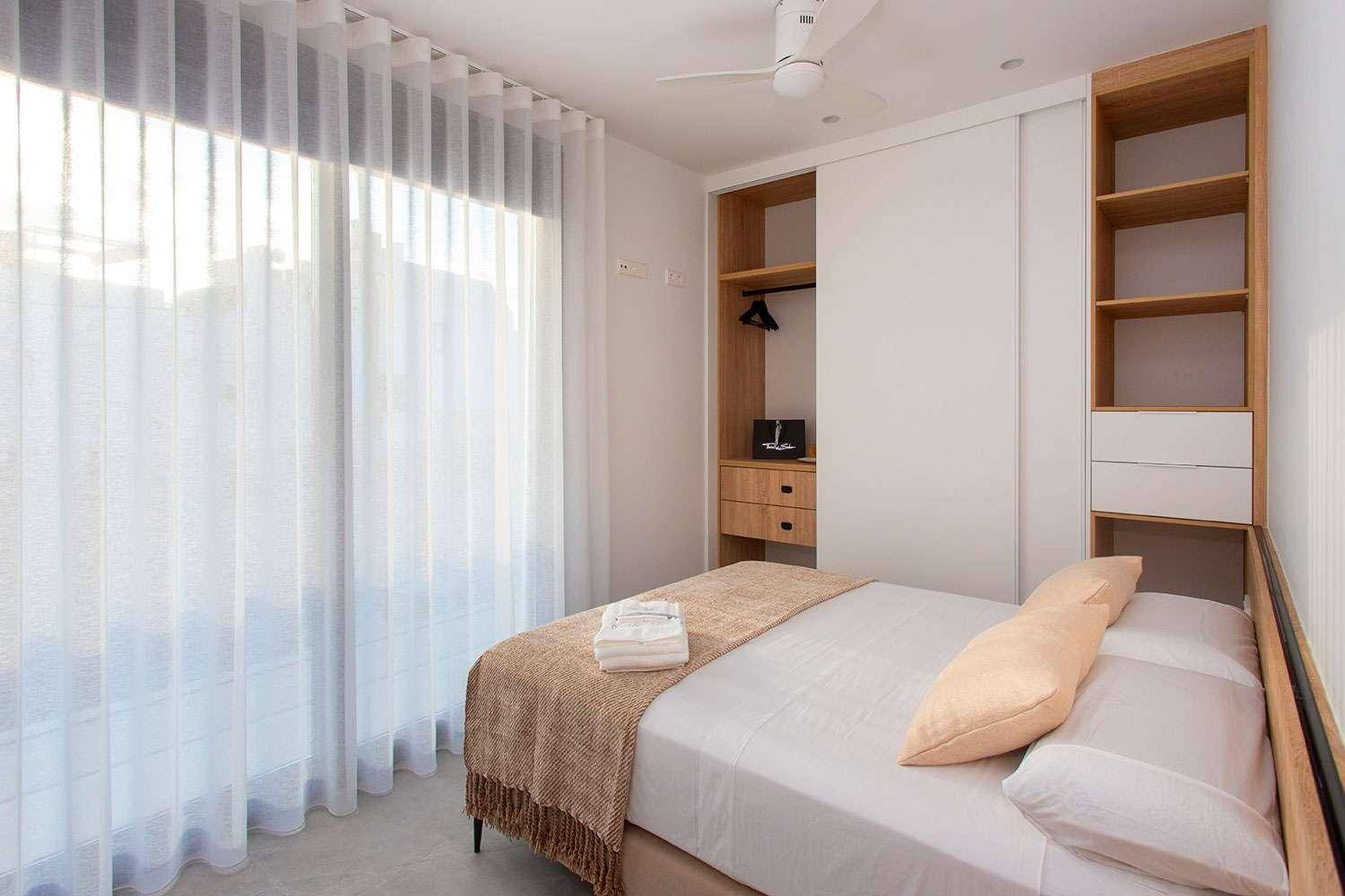 Helles Schlafzimmer mit Einbauschränken, Deckenventilator und großen Fenstern für gute Belüftung.