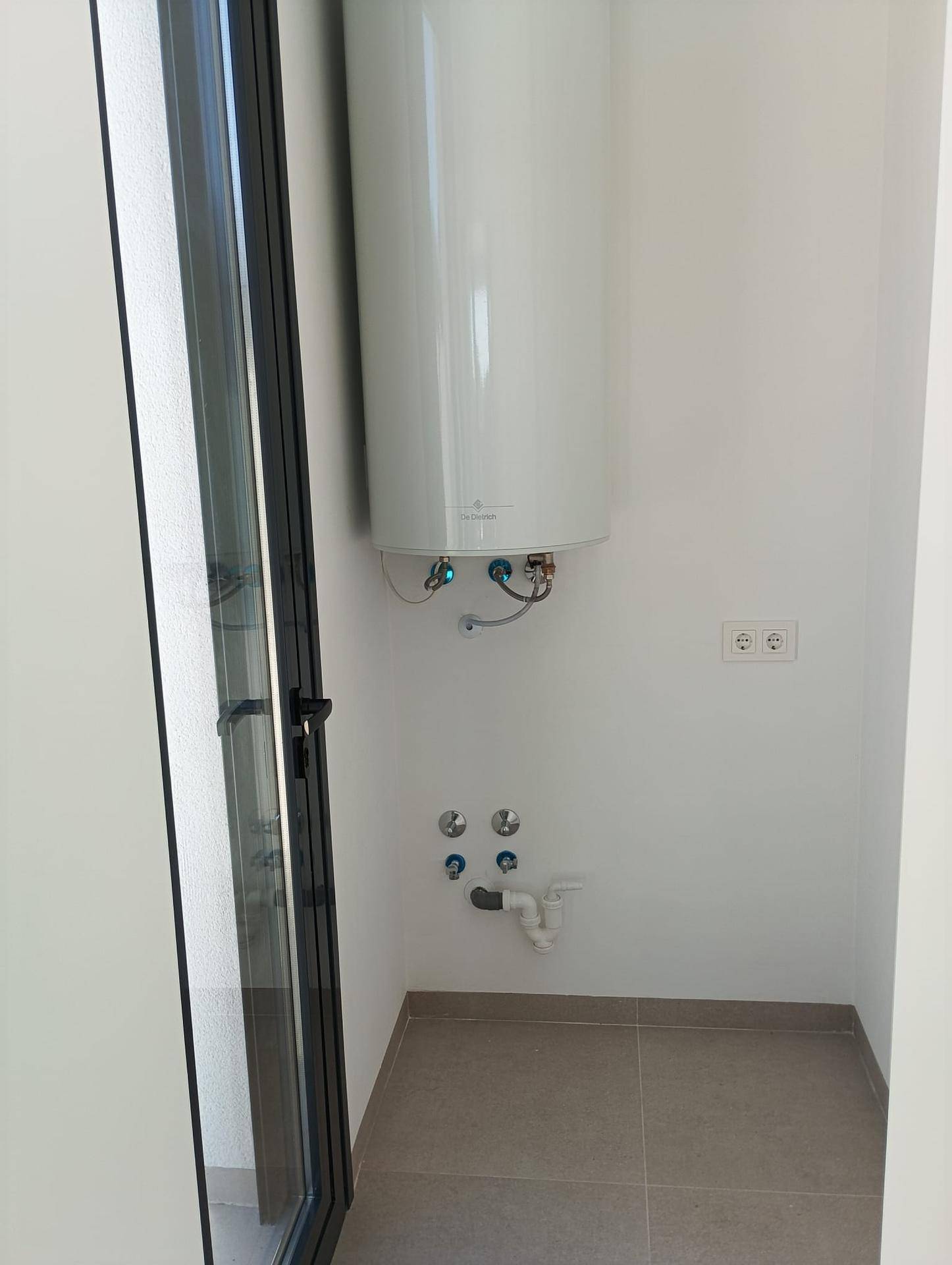 Heller Hauswirtschaftsraum mit Warmwasserboiler und Anschlussmöglichkeiten für Geräte.