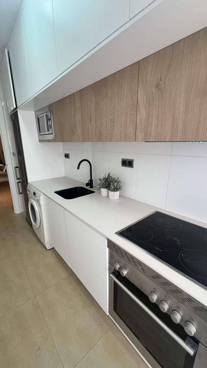 Funktionale Küche mit Backofen, Induktionskochfeld, Spüle und Mikrowelle, in hellem Design.