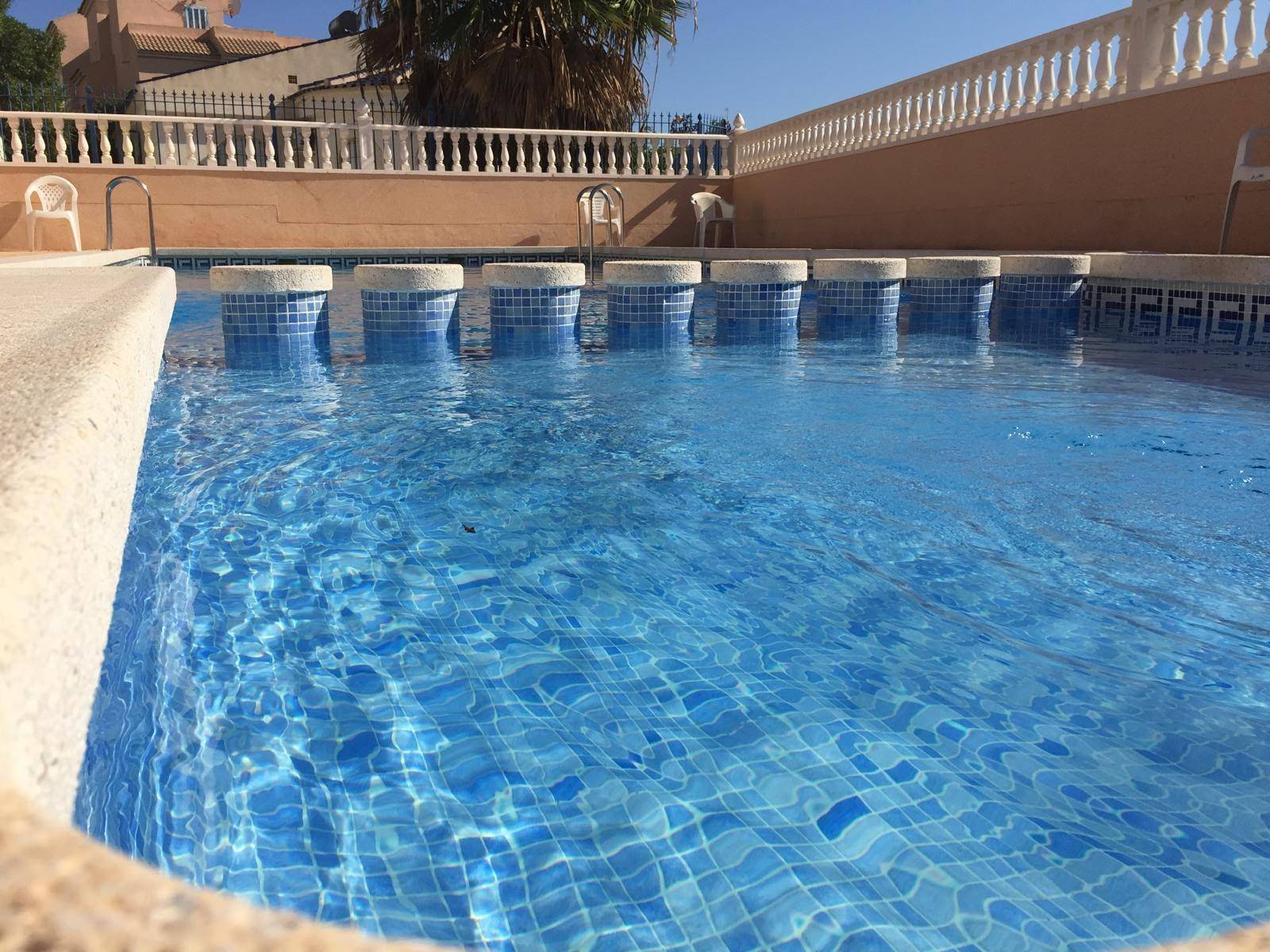 Nahaufnahme des Pools mit blauen Mosaikfliesen und dekorativen Elementen im Wasser.