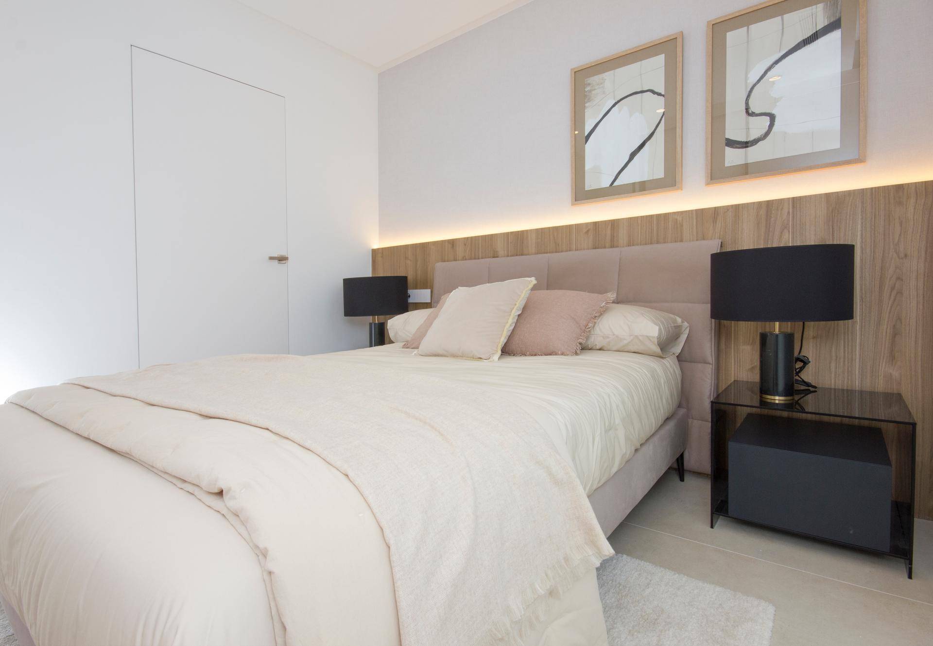 Modernes Schlafzimmer mit beigem Bett, Holzakzenten und großen Fenstern.