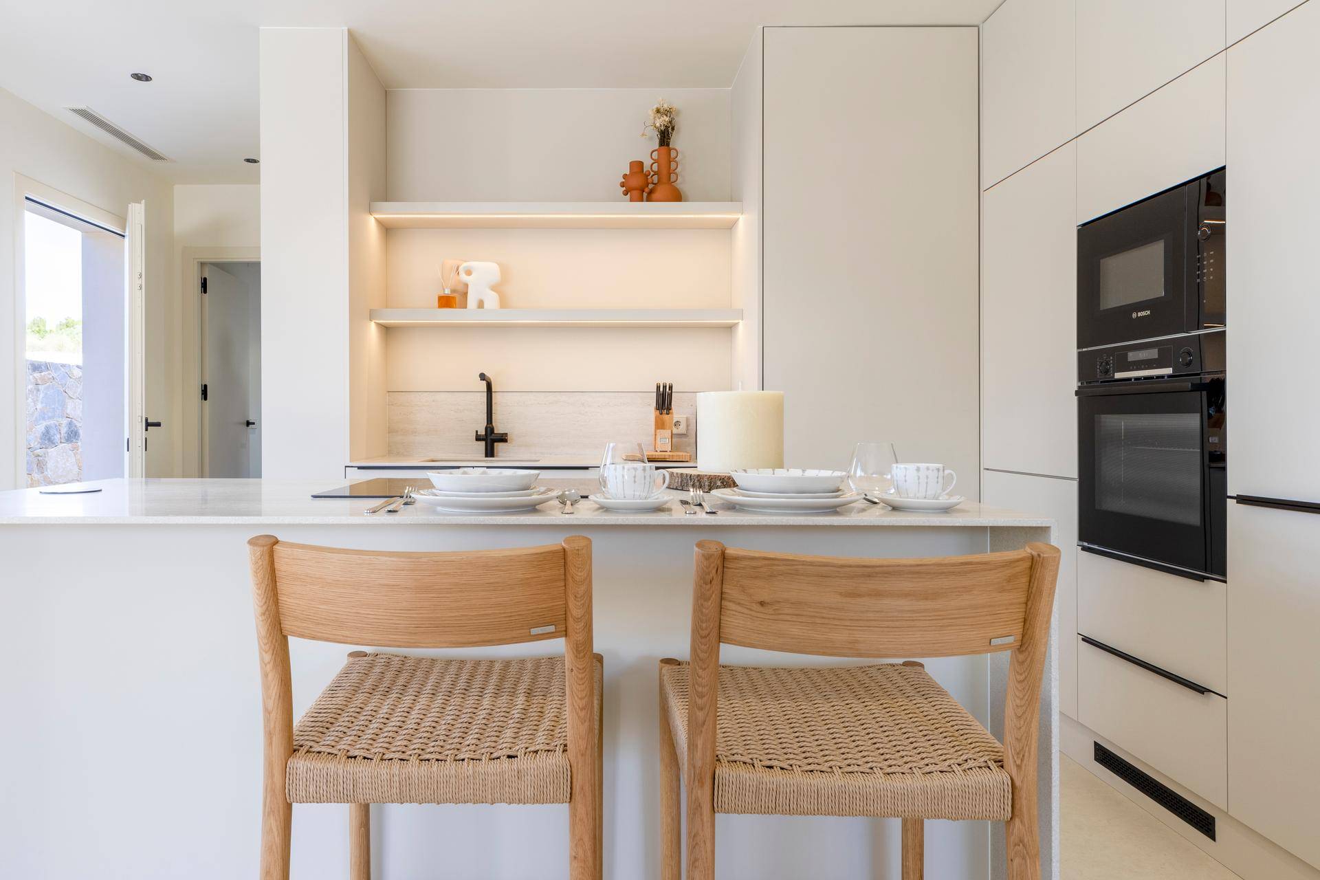 Moderne Küche mit integrierten Geräten, Kochinsel und Frühstücksbar mit Barhockern.