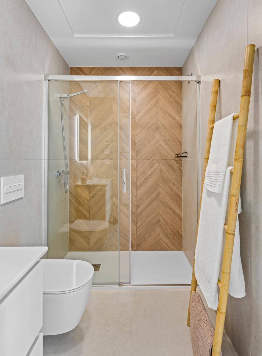 Modernes Badezimmer mit begehbarer Dusche und Holzakzenten an der Wand.