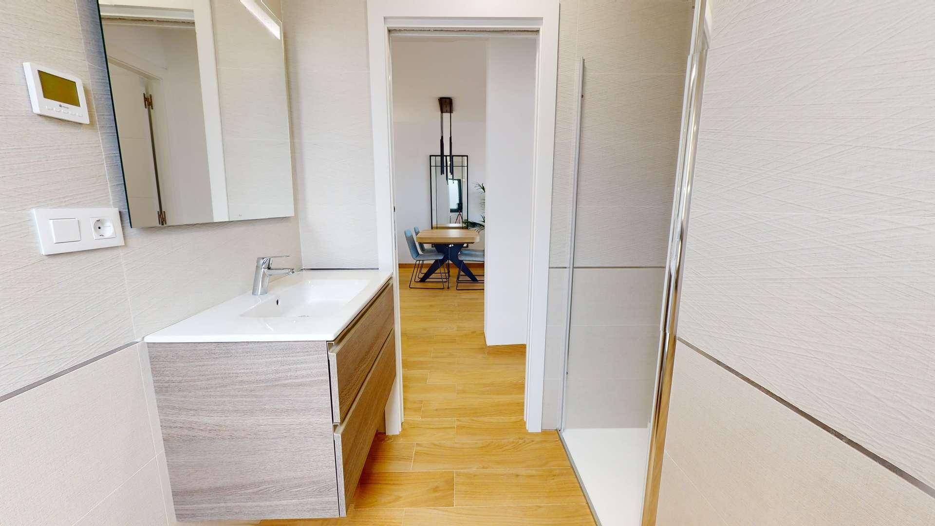 Modernes Badezimmer mit schwebendem Waschtisch, Spiegelschrank und begehbarer Dusche.